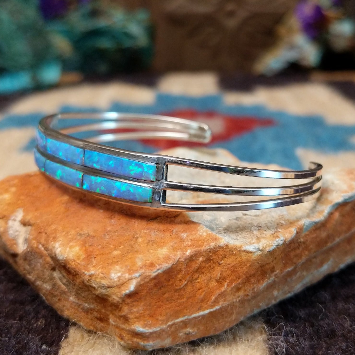 Dual row manmade opal inlay cuff by Jamie Johnson, featuring shimmering opal inlay with vibrant flashes of color set in handcrafted Southwestern-inspired metalwork. Side view.