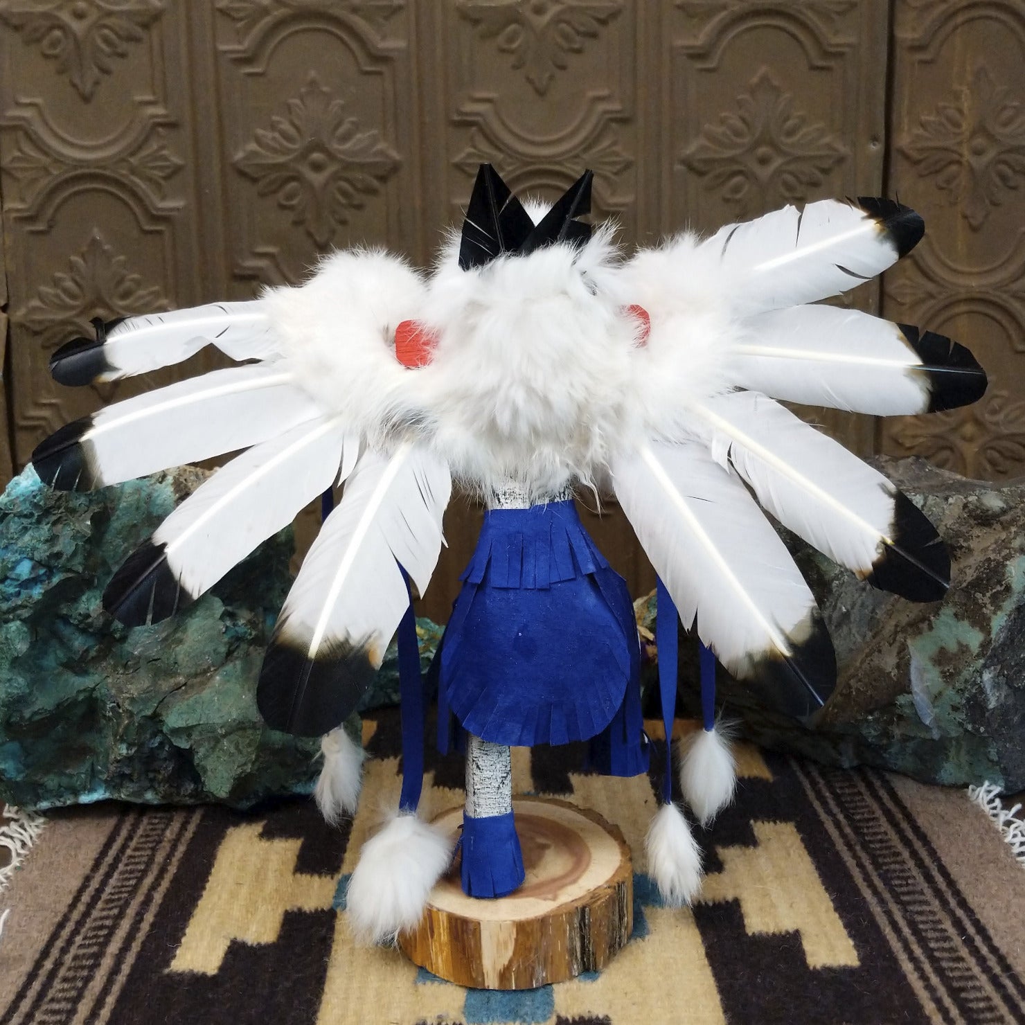 Navajo-made eagle kachina doll by M. C. with outstretched feathered wings, blue mask, yellow beak, and white feather collar.