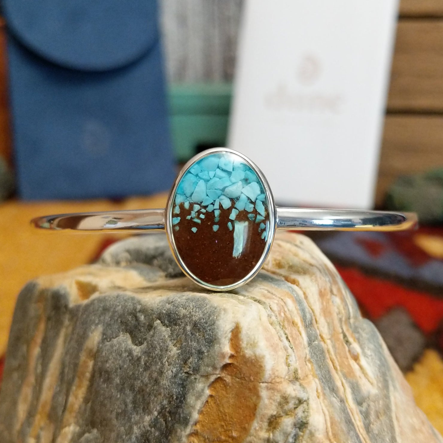 Oval cuff with a silver-plated brass frame, featuring turquoise and brown sand.