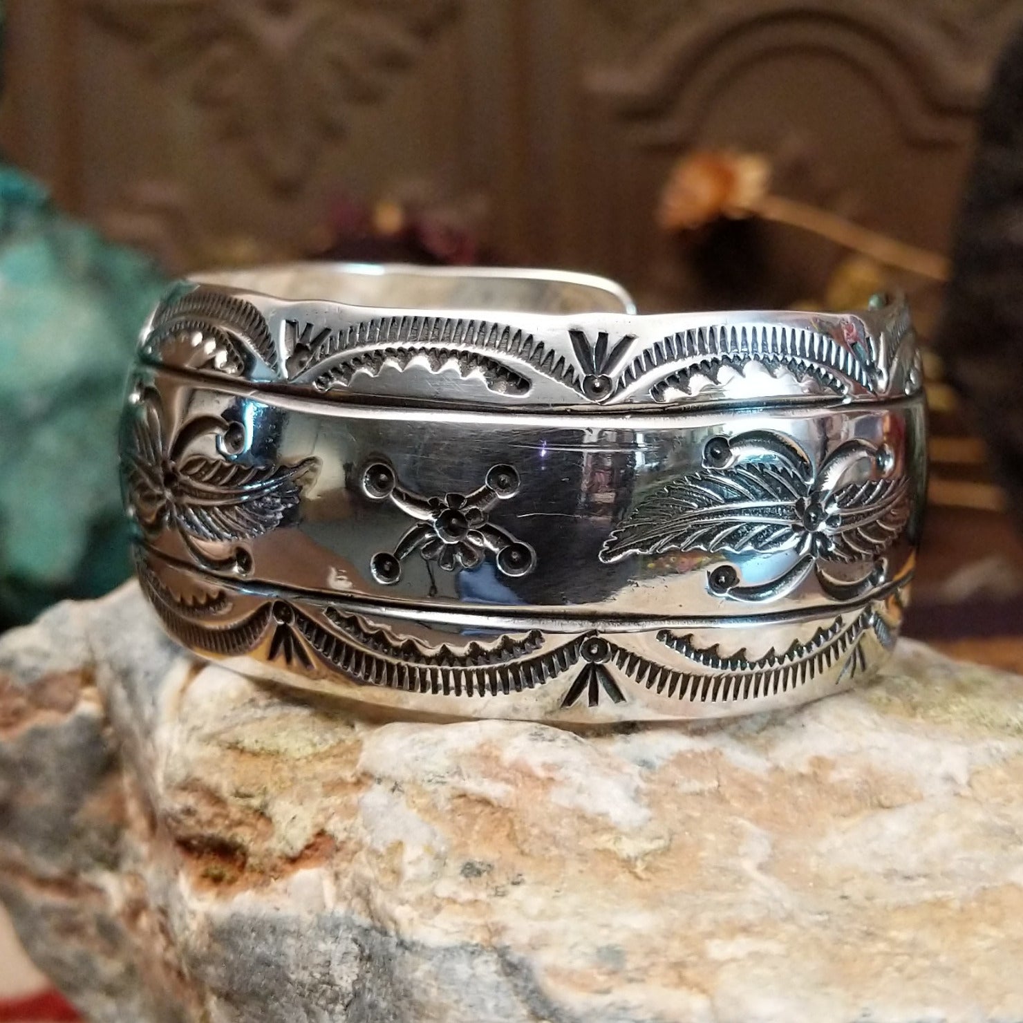 Wide sterling silver cuff bracelet with a raised leaf motif, hand-stamped details, and oxidized accents.