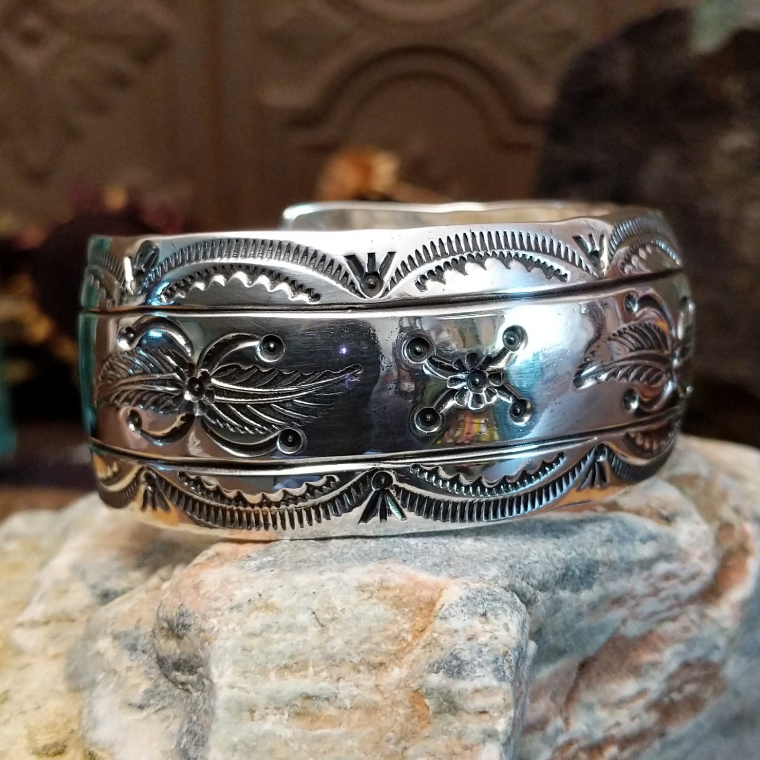 Wide sterling silver cuff bracelet with a raised leaf motif, hand-stamped details, and oxidized accents.