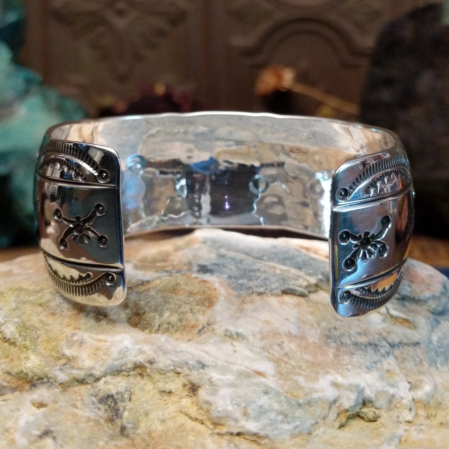 Wide sterling silver cuff bracelet with a raised leaf motif, hand-stamped details, and oxidized accents.