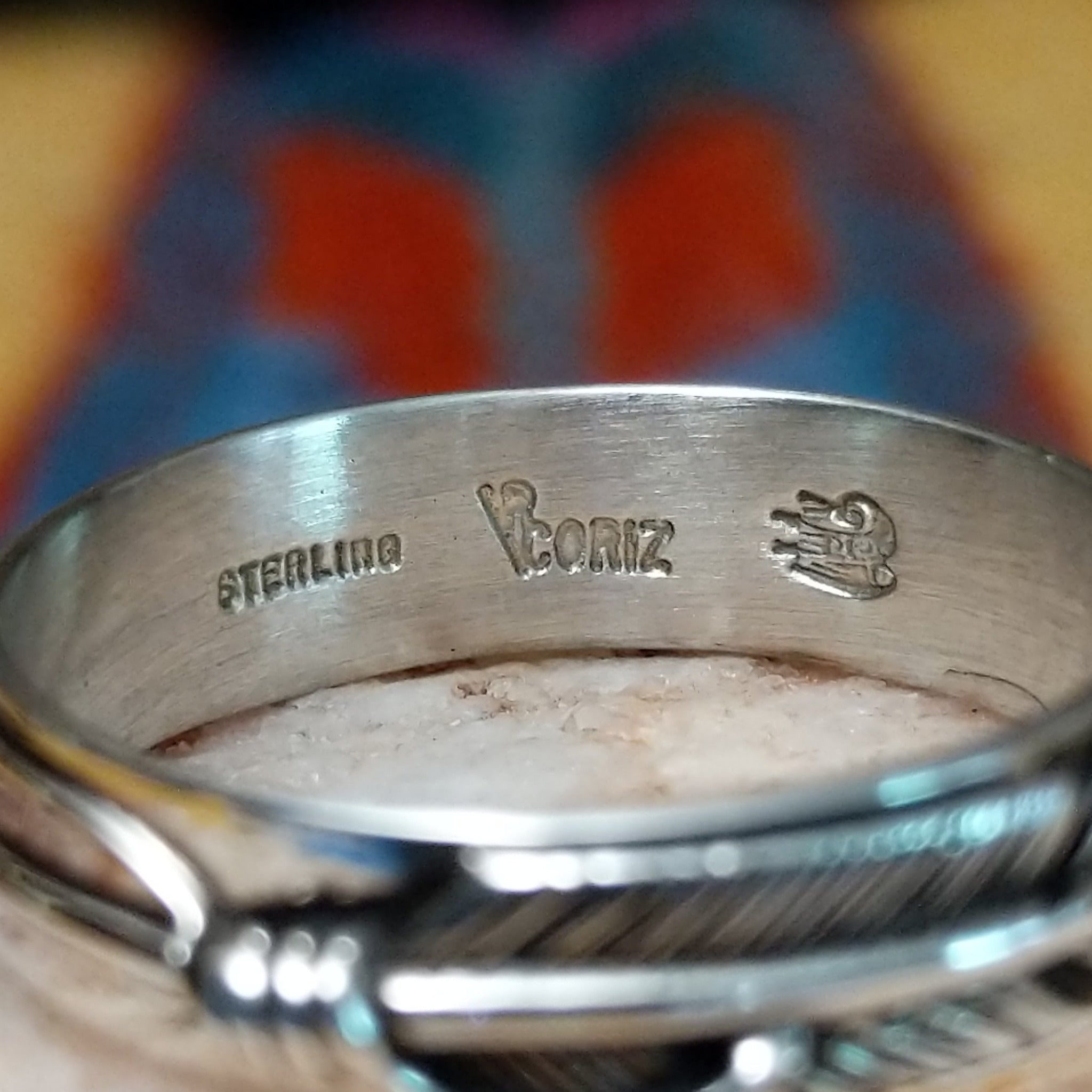 Feather loop ring by Raymond Coriz, featuring a detailed handcrafted feather design wrapped around a polished sterling silver band with traditional Southwestern-inspired craftsmanship. Artisan and Sterling Silver stamp.