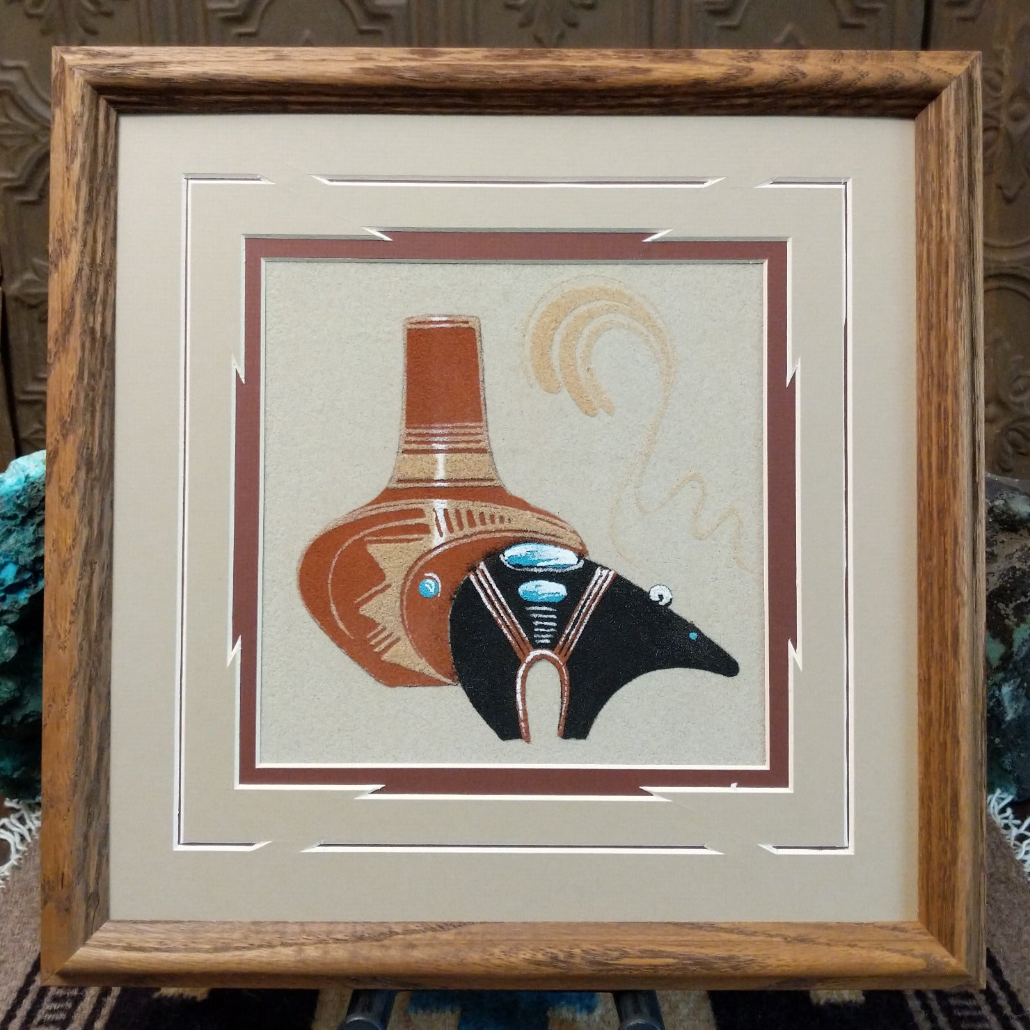 Framed Navajo sand painting of a fetish bear and pottery vessel with turquoise accents.