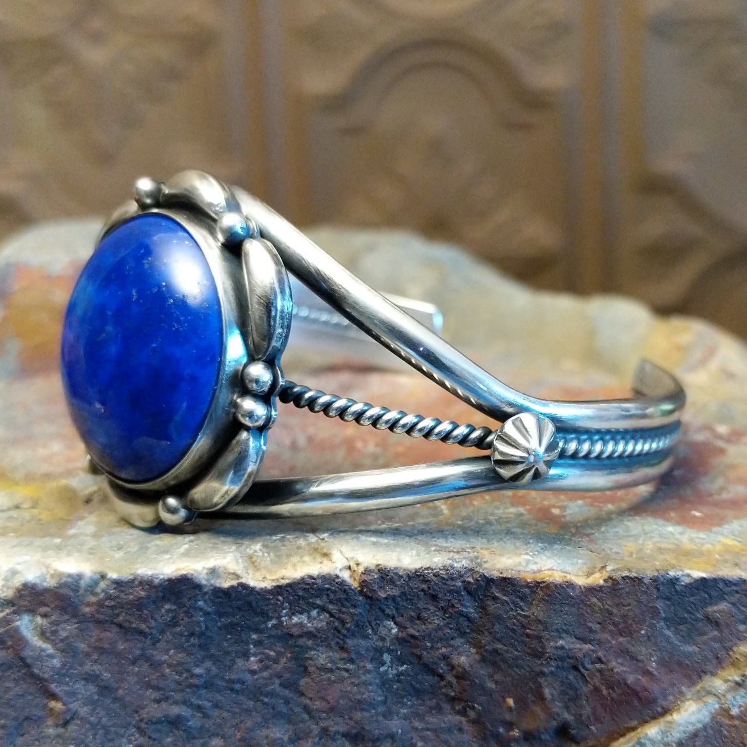 Sterling silver cuff with lapis set in the round bezel and floral silverwork along the band.