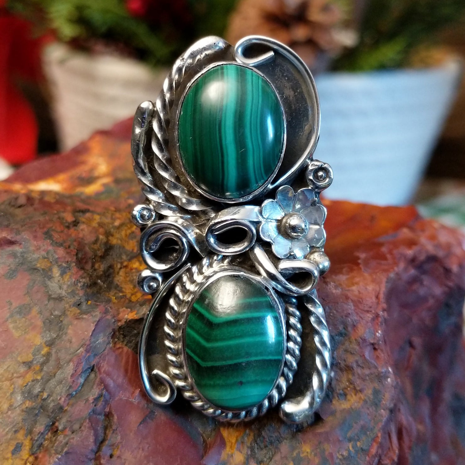 Sterling silver ring with two malachite stones set in the bezels framed by twisted rope and floral accents.