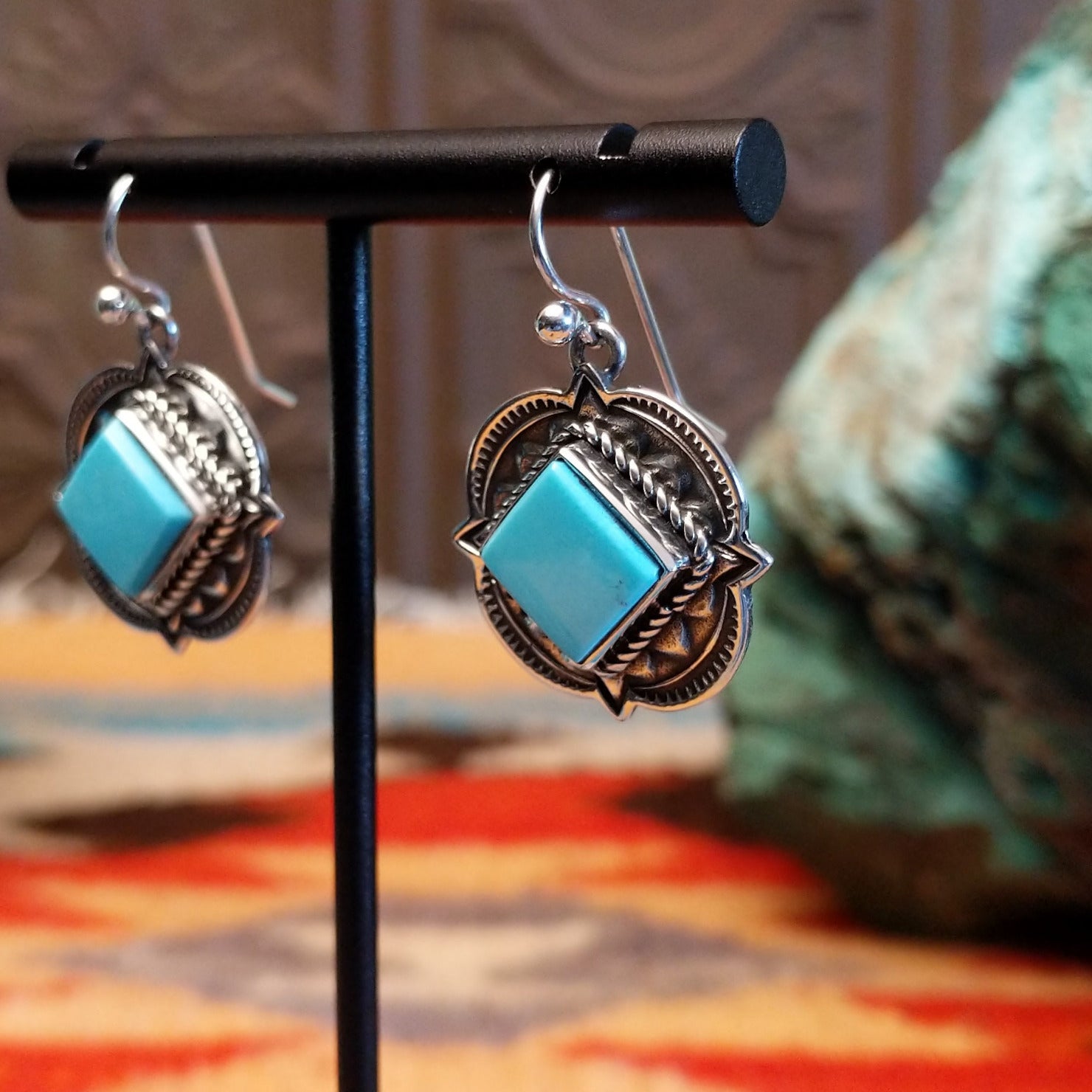 Sterling silver earrings with Kingman turquoise set in diamond-shaped bezels, framed by ornate stamped settings.