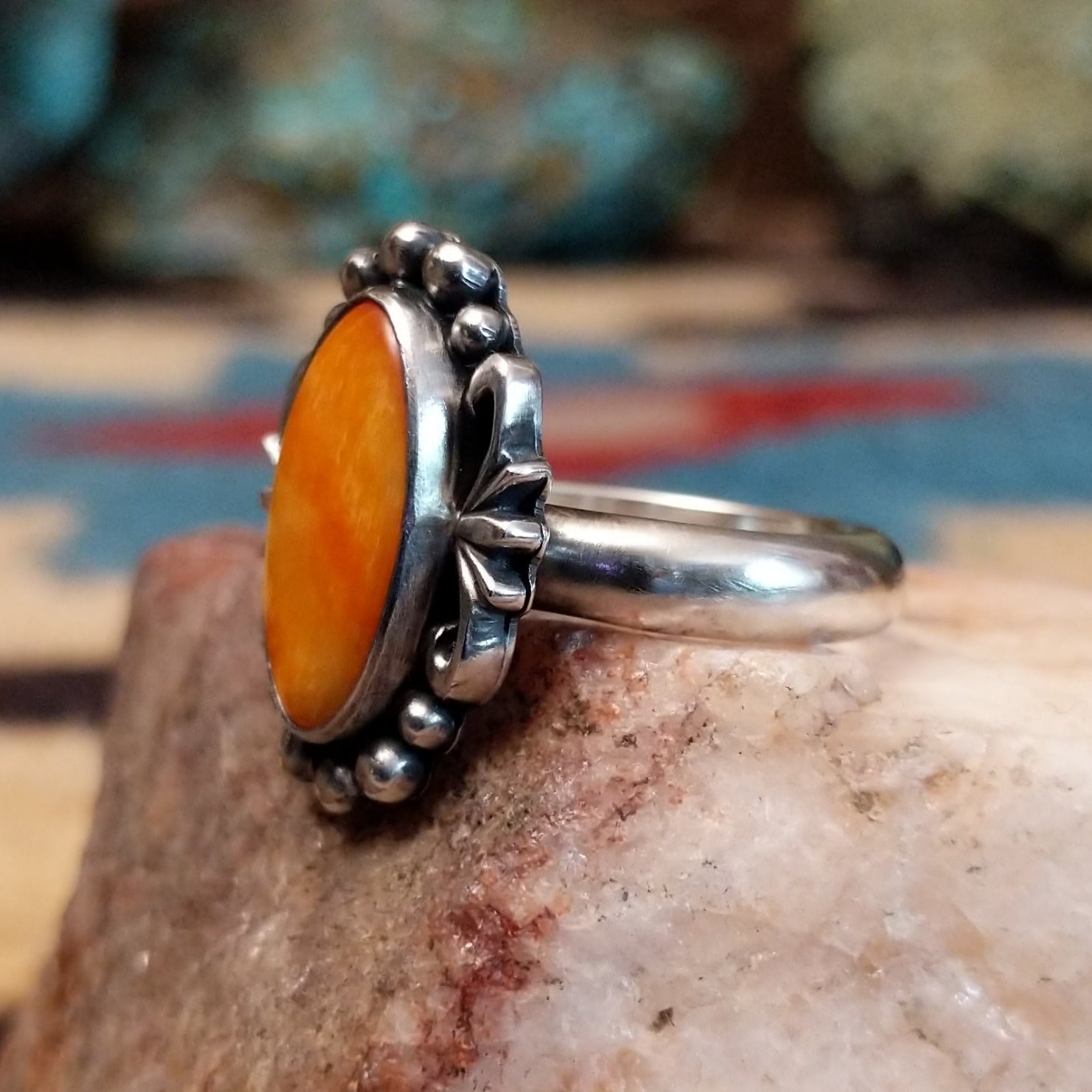 Sterling silver ring with orange oyster shell in an oval bezel.