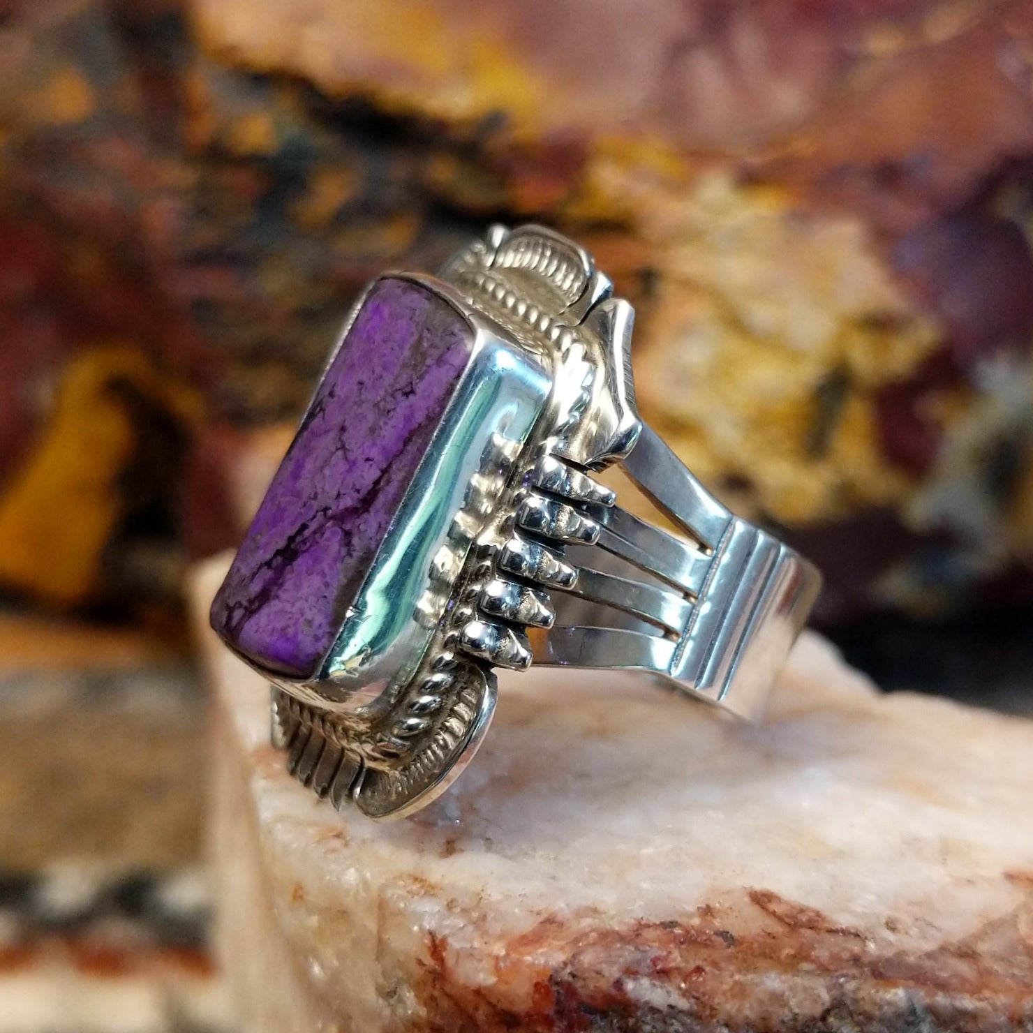 Square sugilite ring set within an intricate silver work bezel.