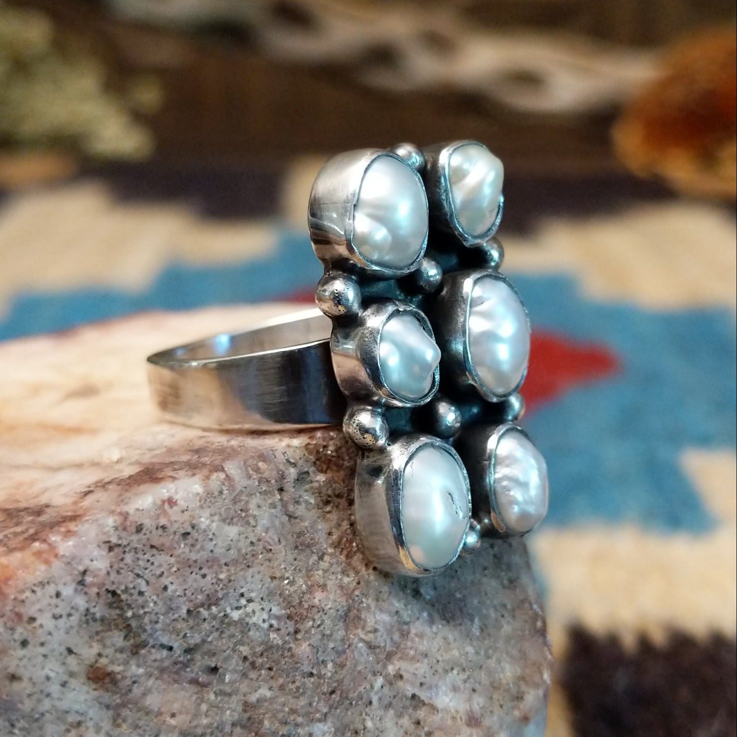 Sterling silver ring with freshwater pearl set in six bezels, framed by dotted accents.