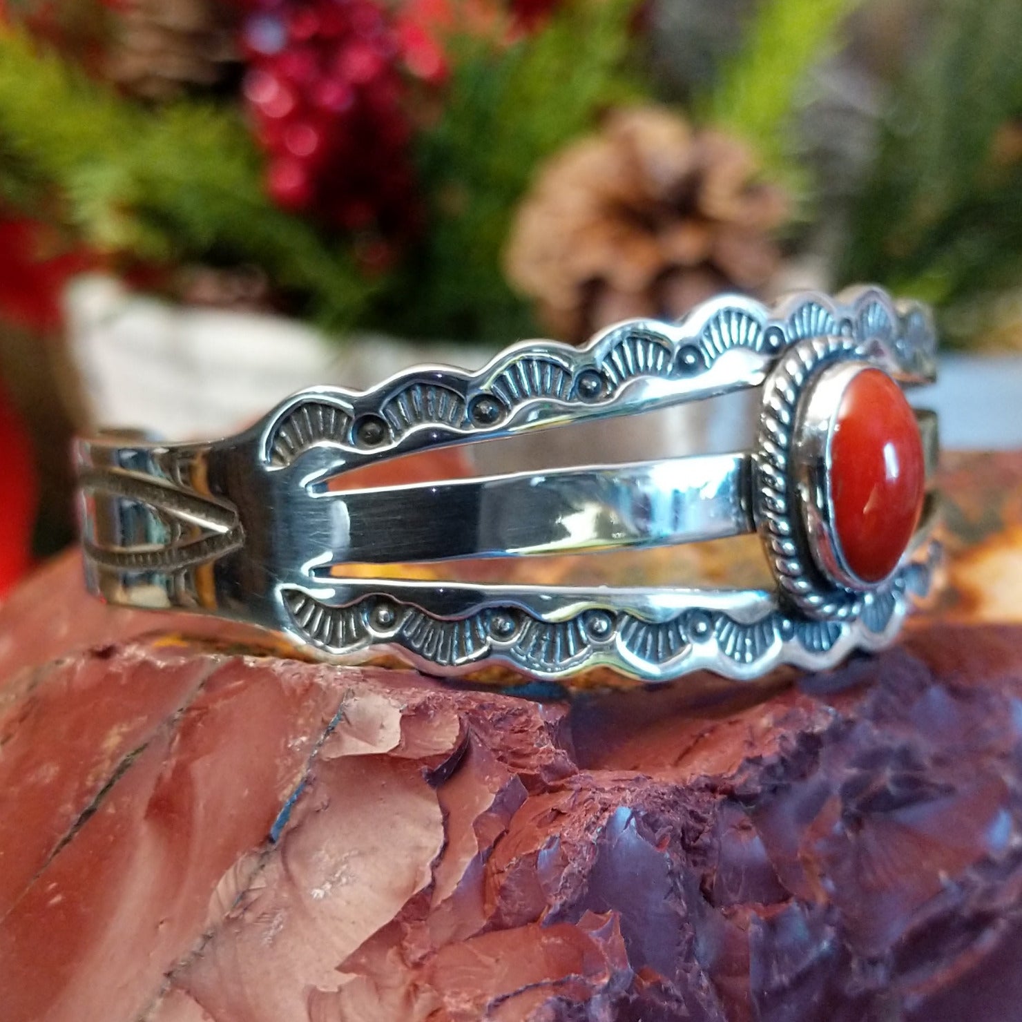 Sterling silver cuff with stamped, frilled edges and coral framed by twisted rope accent.