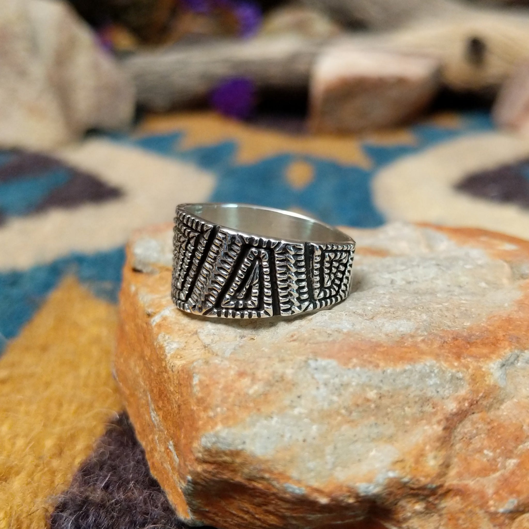 Sterling silver geometric band ring by Elgin Tom with hand-stamped spiral patterns; side view.