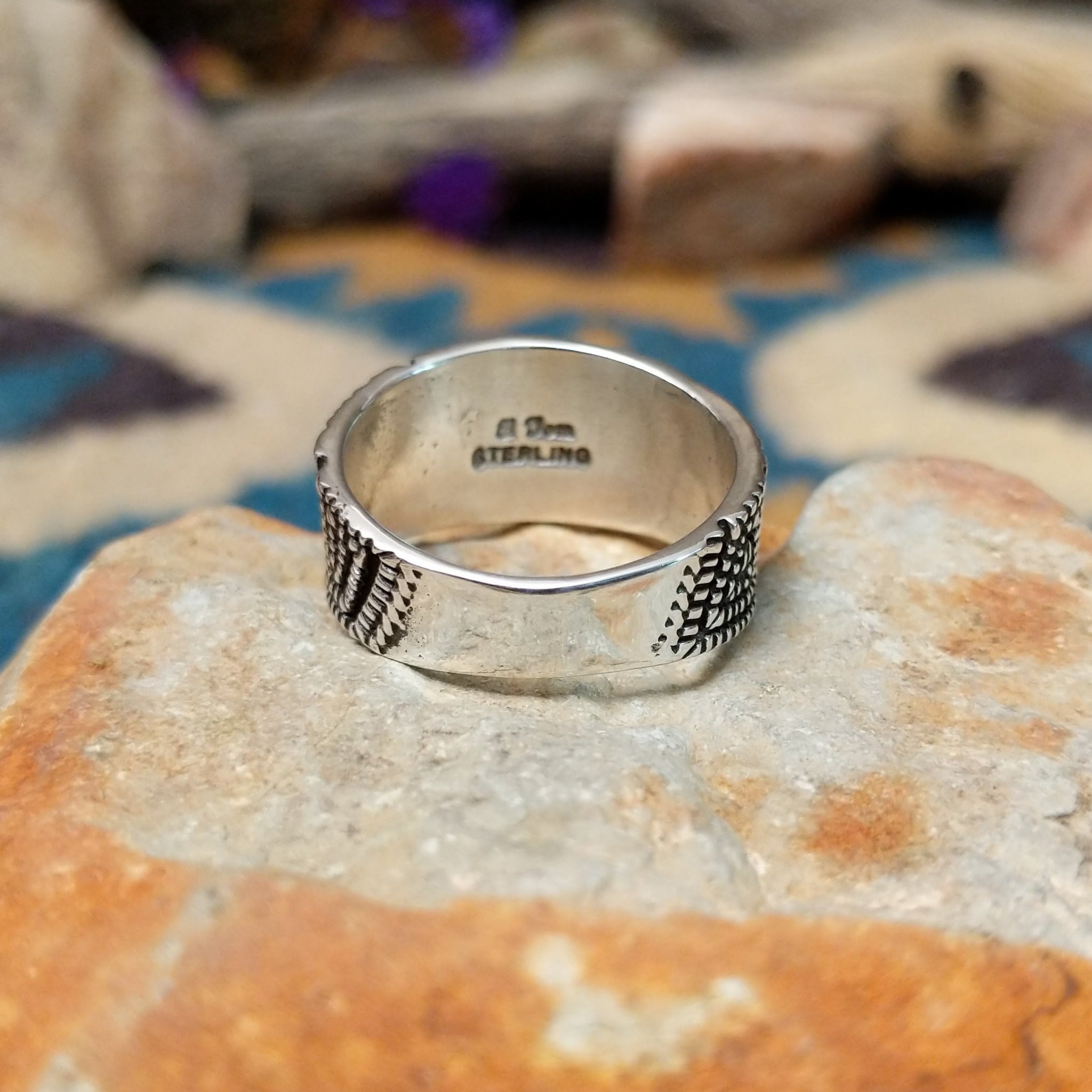 Sterling silver geometric band ring by Elgin Tom with hand-stamped spiral patterns; underside view.