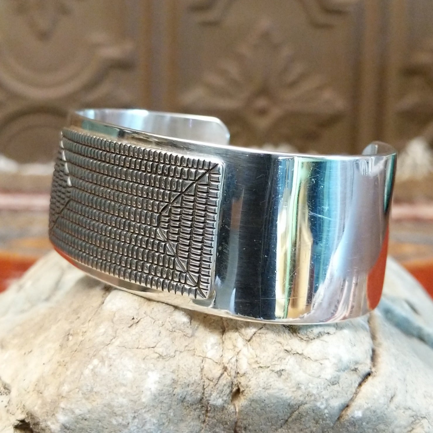 Sterling silver cuff with geometrical stamped centerpiece and polished finish.