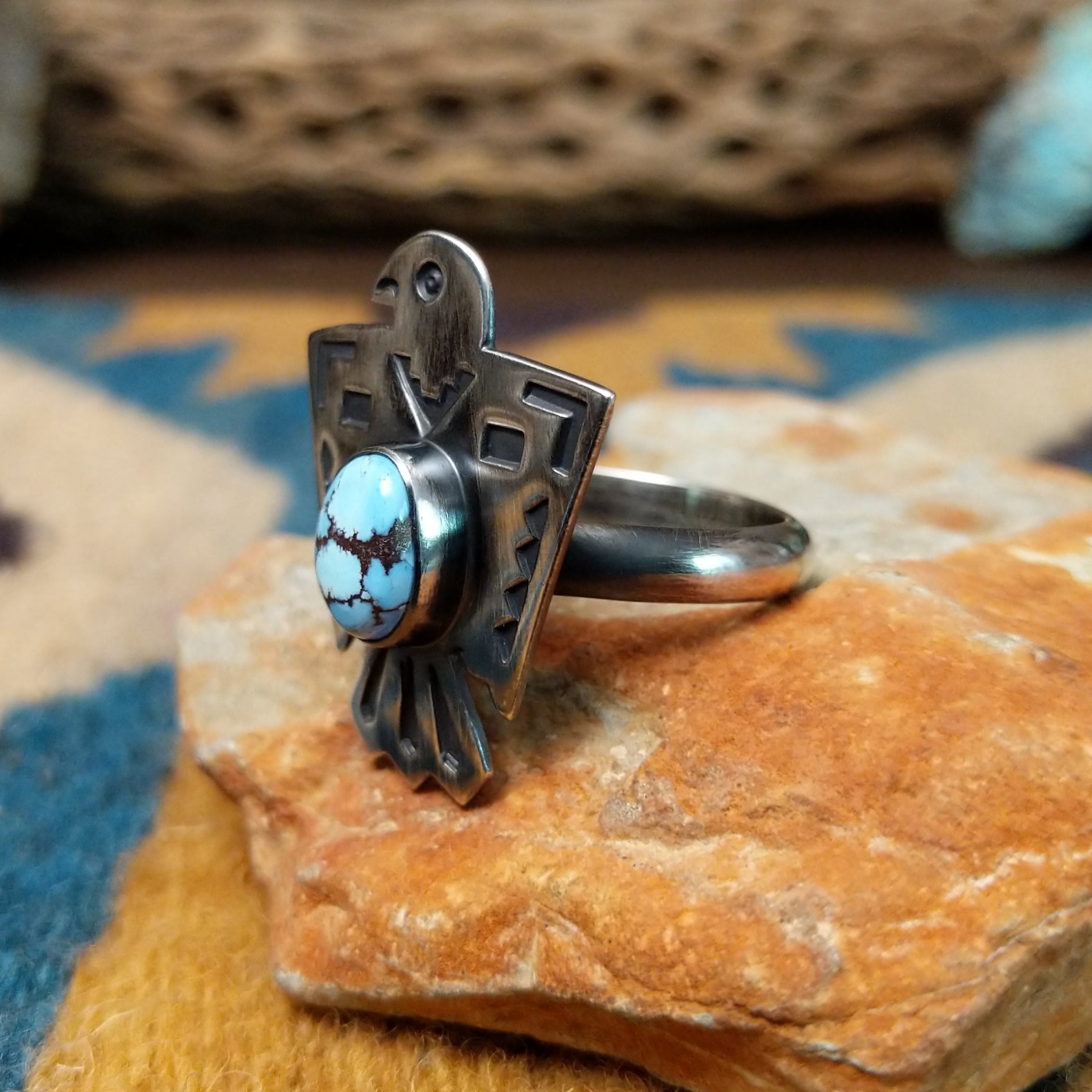 Handcrafted Navajo sterling silver Thunderbird ring by Lowell Draper featuring an oval Golden Hill turquoise cabochon with natural dark matrix, set in a traditional hand-cut Thunderbird design with an oxidized finish; side view.