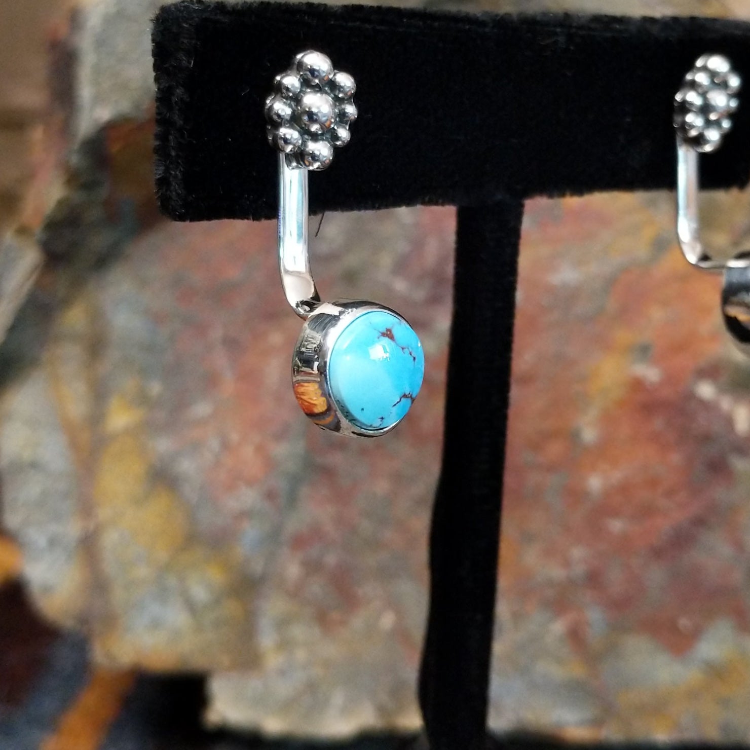 Partial side view of Golden Hills turquoise adjustable earrings displaying a Golden Hills turquoise with light brown matrix veining in a sterling silver frame with a smooth bezel, crafted by Navajo artist Terry Wood.