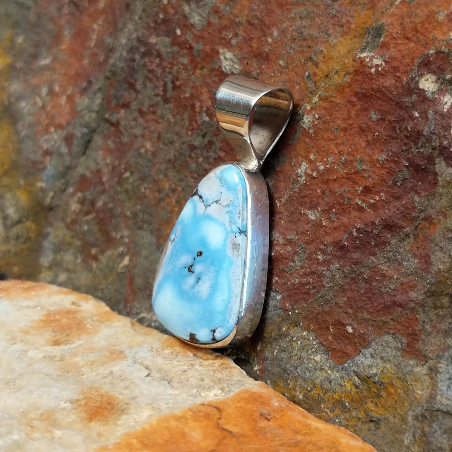 The side of the pendant shows the smooth bezel with the turquoise stone.