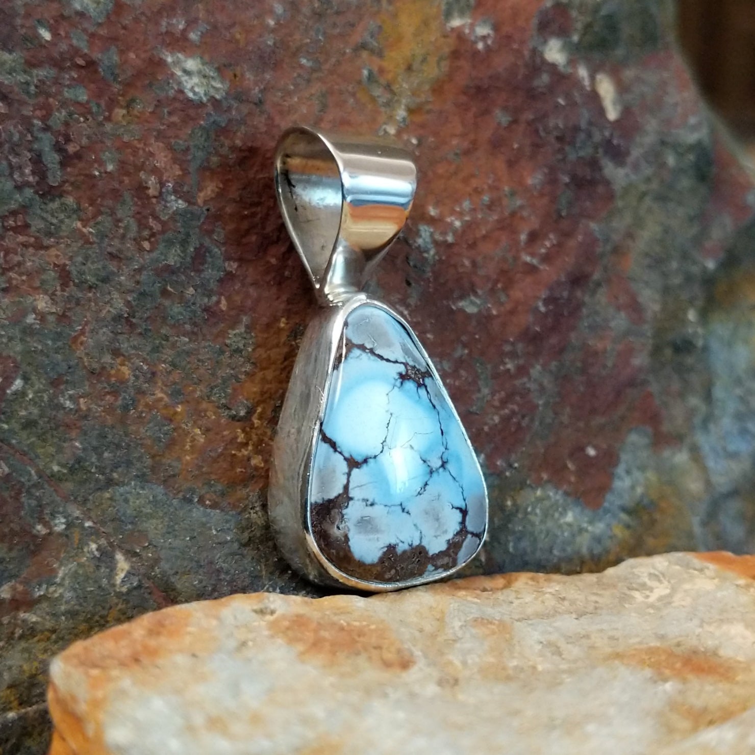 The side of the pendant shows the smooth bezel with the triangular turquoise stone.