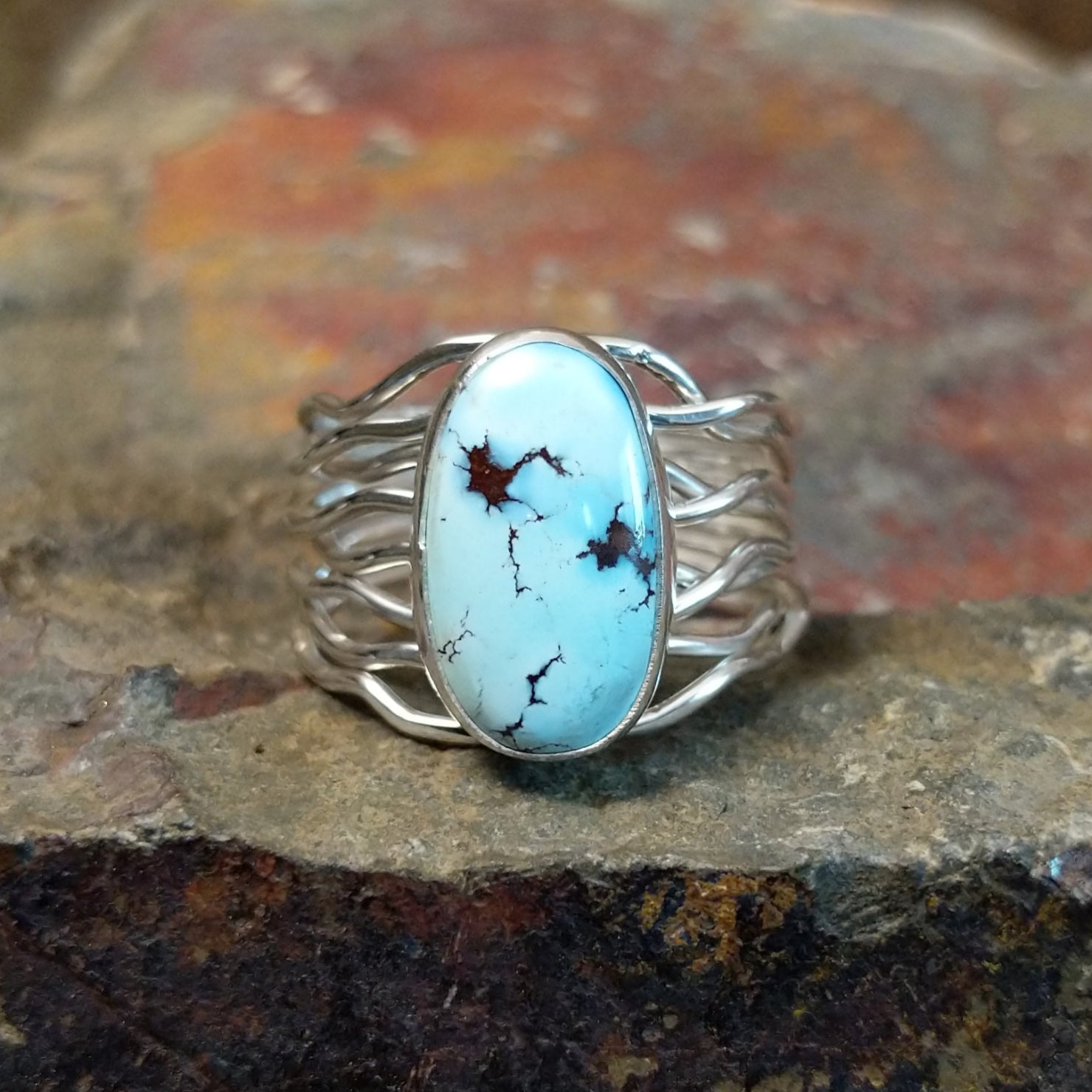 Silver ring with an oval Golden Hills turquoise stone in a smooth bezel, wrapped by a twisted silver band.