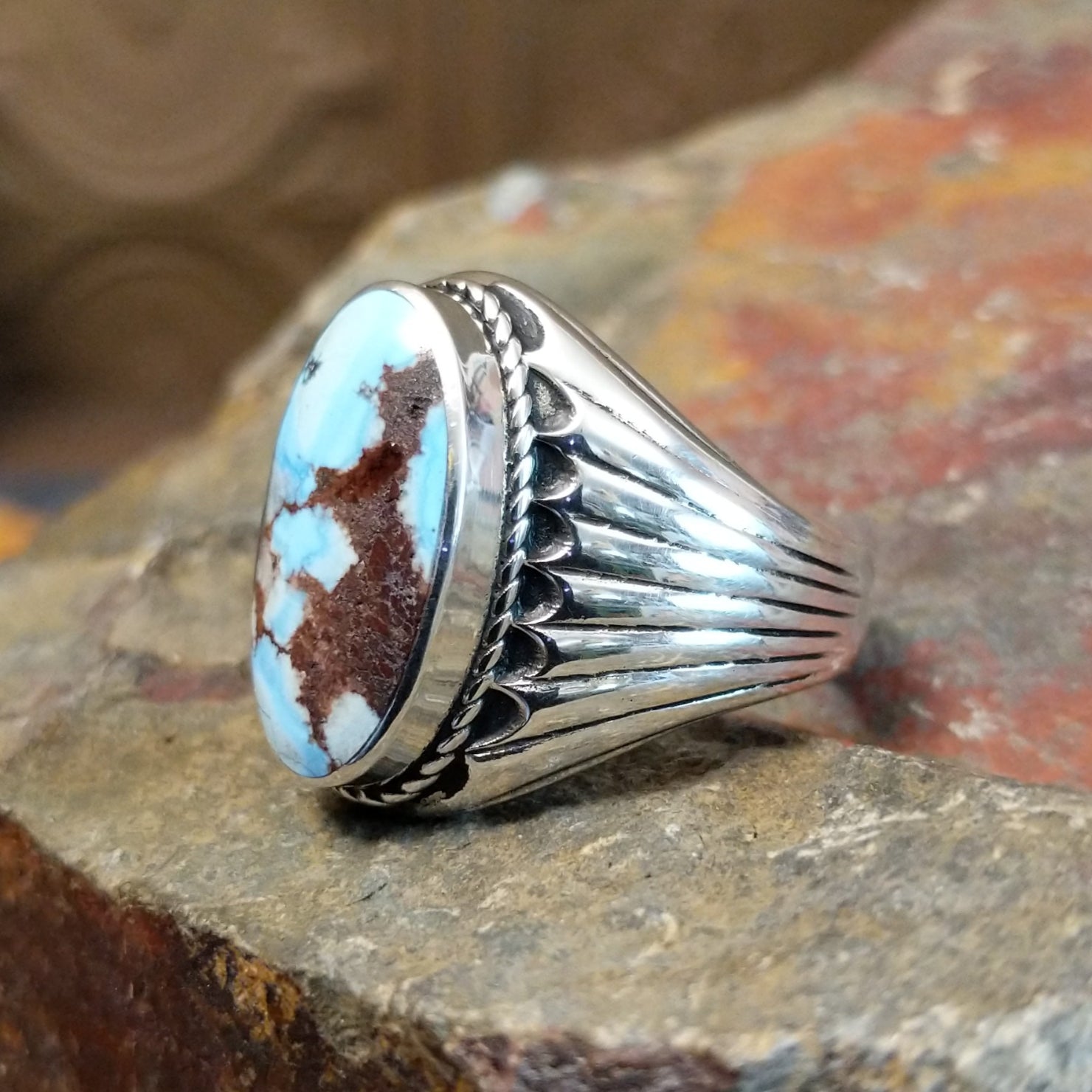 The ring’s band features ribbed silver detailing, complementing the turquoise’s earthy tones.