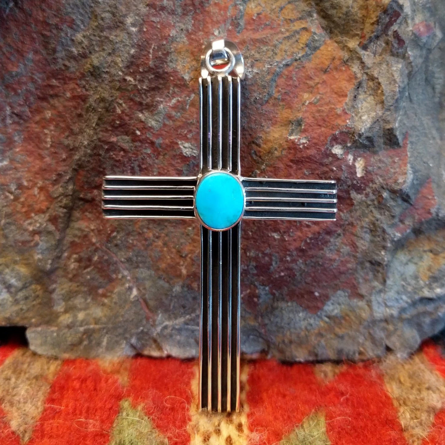 Grooved sterling silver cross pendant with single turquoise stone by Navajo artisan Francis Jones.