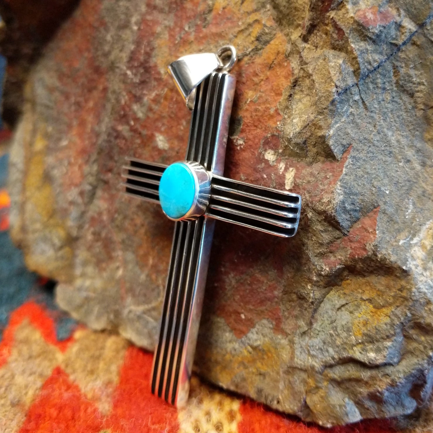 Grooved sterling silver cross pendant with single turquoise stone by Navajo artisan Francis Jones.