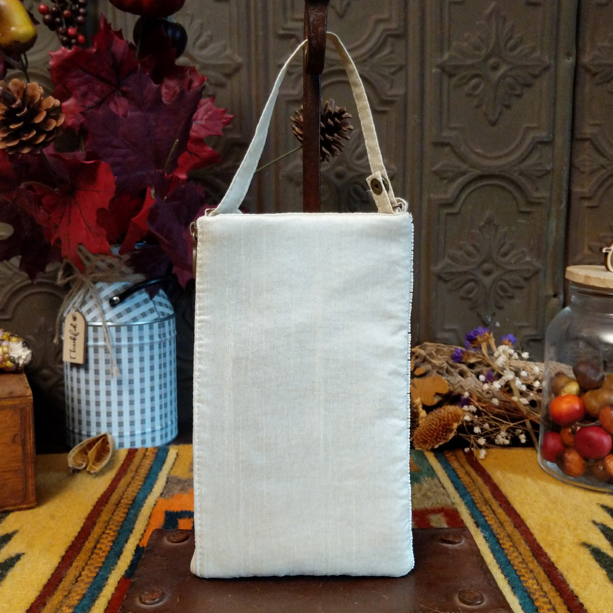 Herd Club Bag by Bamboo Trading featuring embroidered and beaded horse portraits in brown, black, cream, and golden tan on a shimmering white beaded background with a coordinating ivory shoulder strap; back side view.