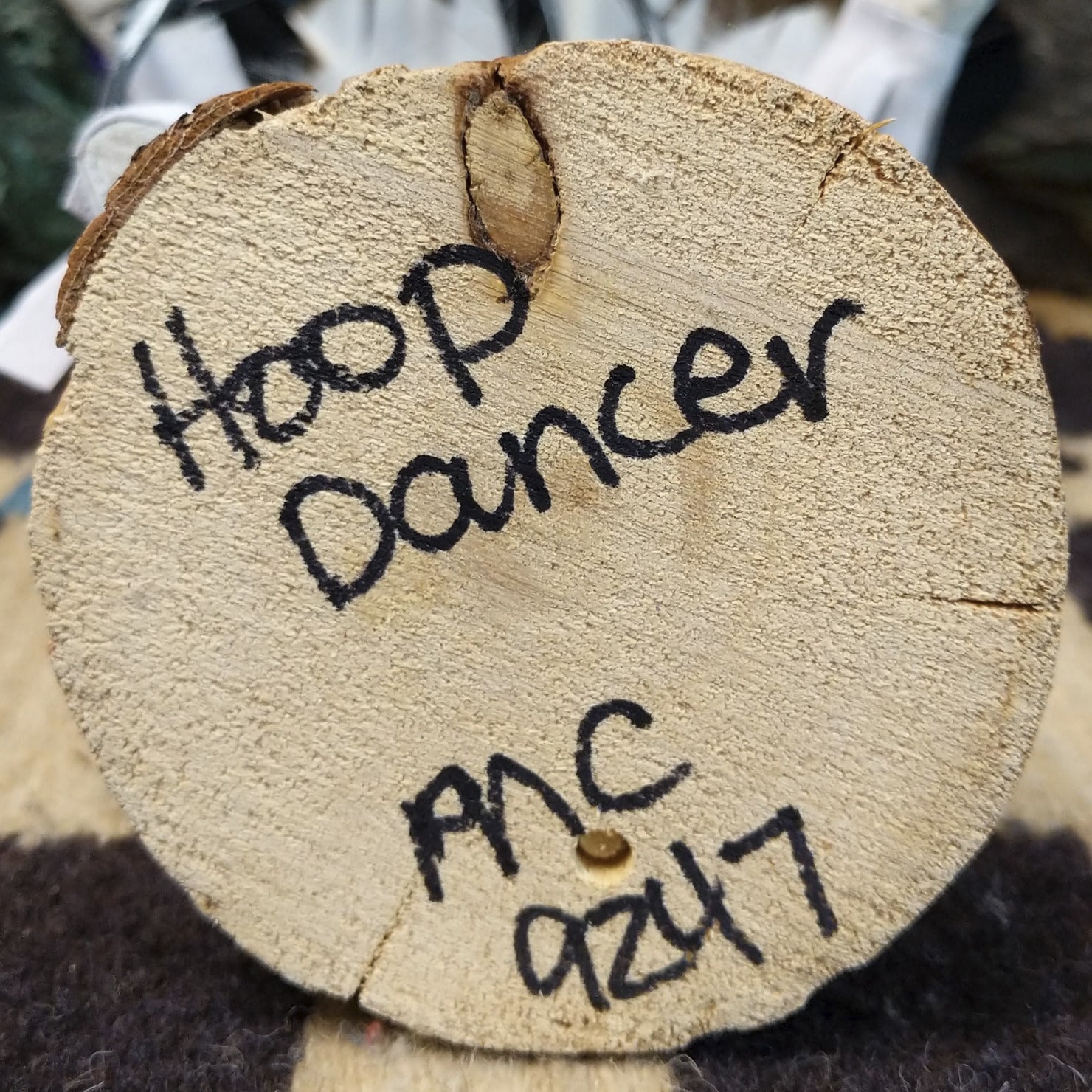 Underside of M. C. hoop dancer kachina doll showing handwritten signature and label on wood base.
