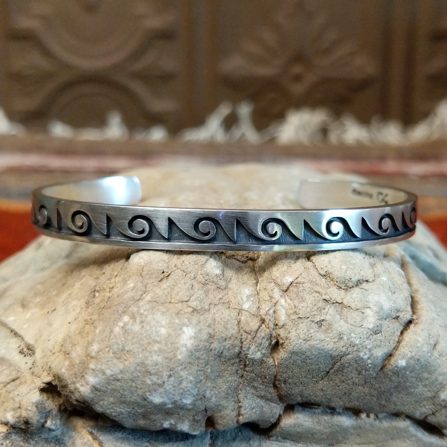 Sterling silver cuff with wave motifs stamped on the surface.