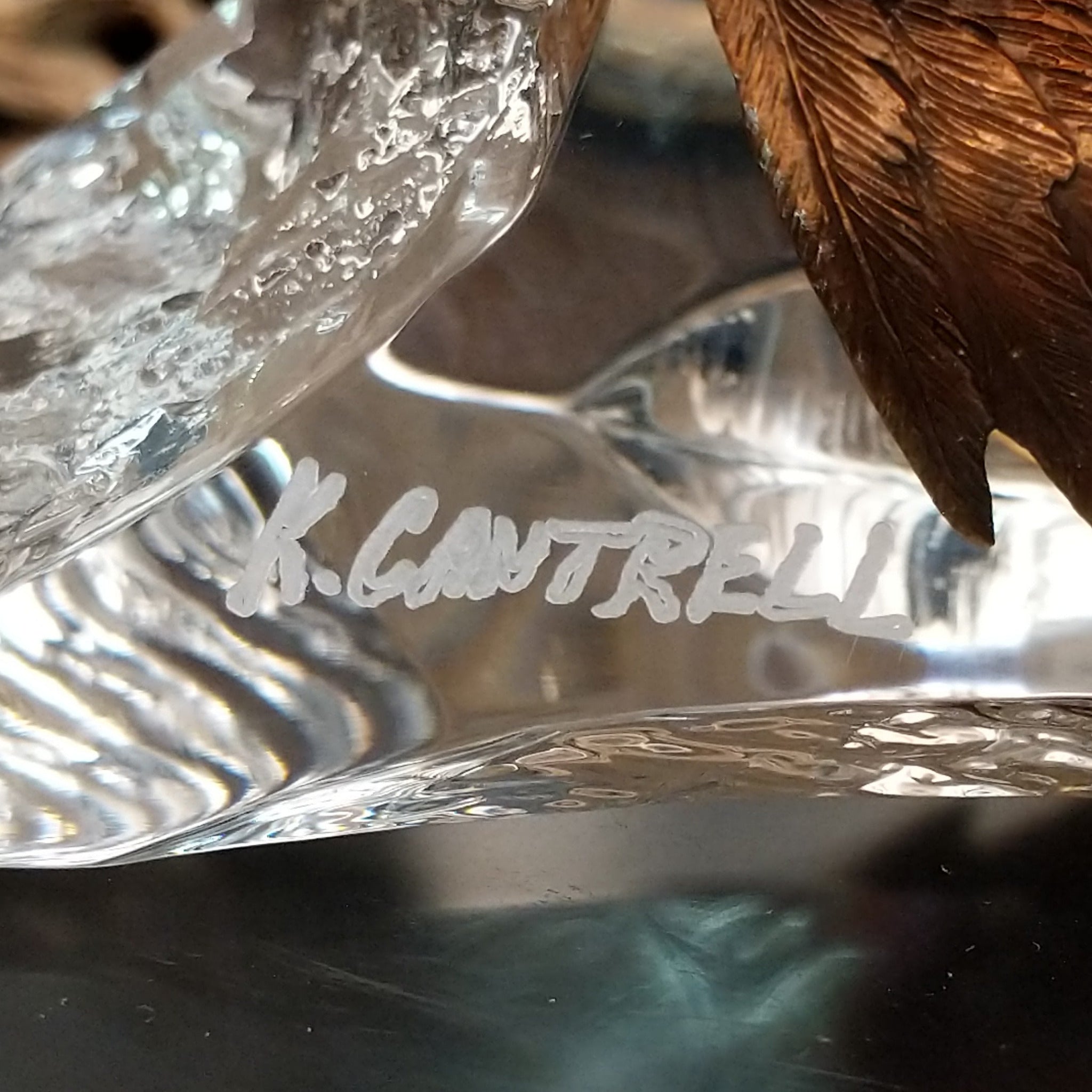 A frosted Lucite sculpture of a bald eagle with a hand-painted bald eagle soaring through the clear crystal interior; artisan signature.
