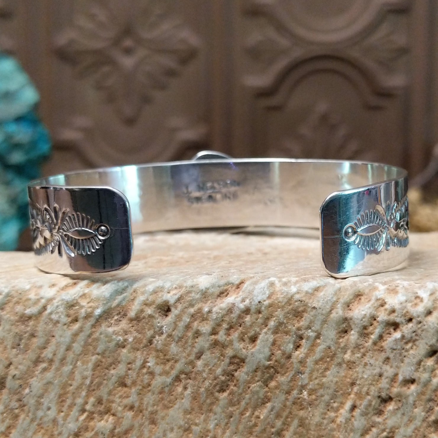 Sterling silver bracelet with turquoise set in the bezel, framed by twisted rope accents and stamping along the polished band.