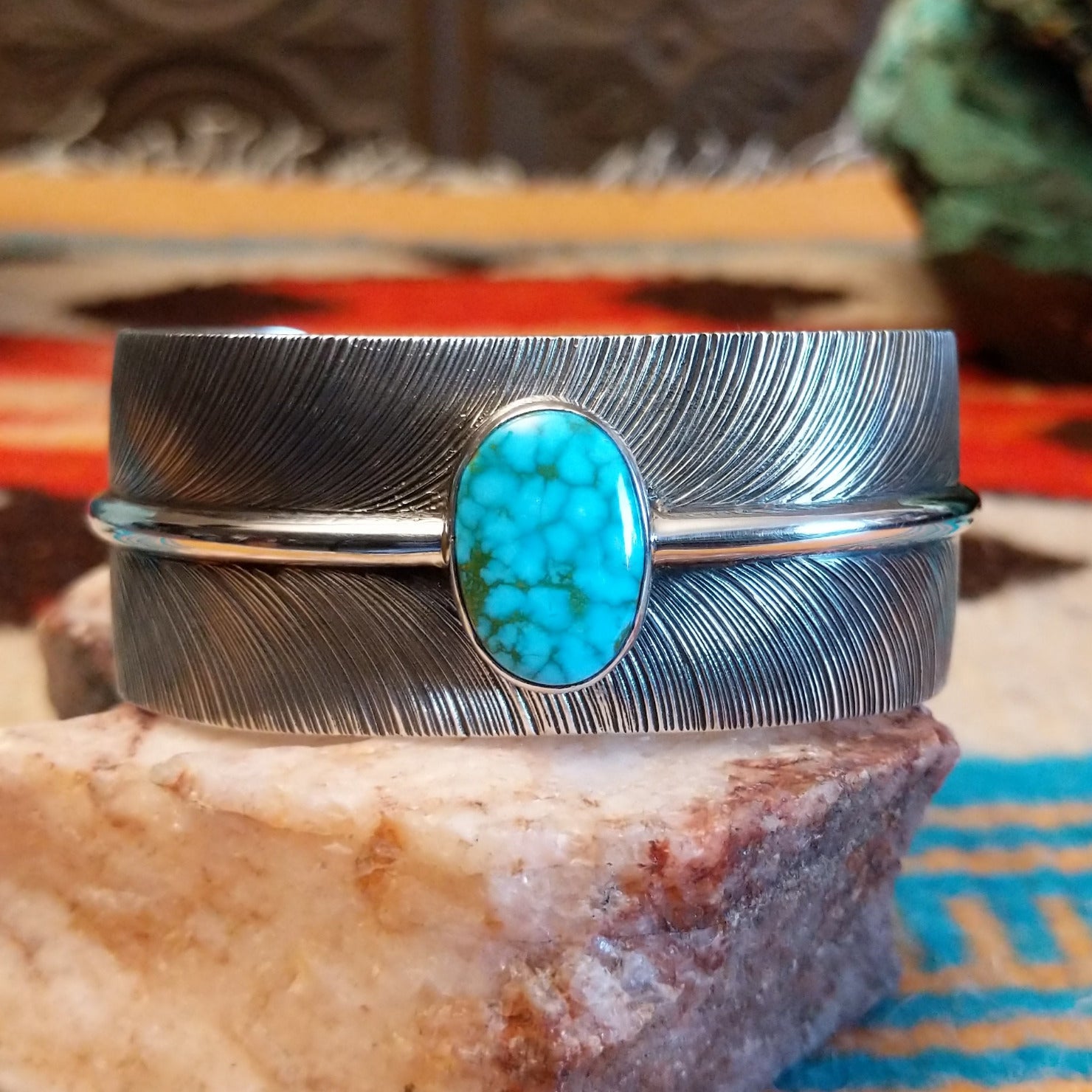 Sterling silver cuff bracelet with Kingman turquoise set in an oval bezel and feather band design.