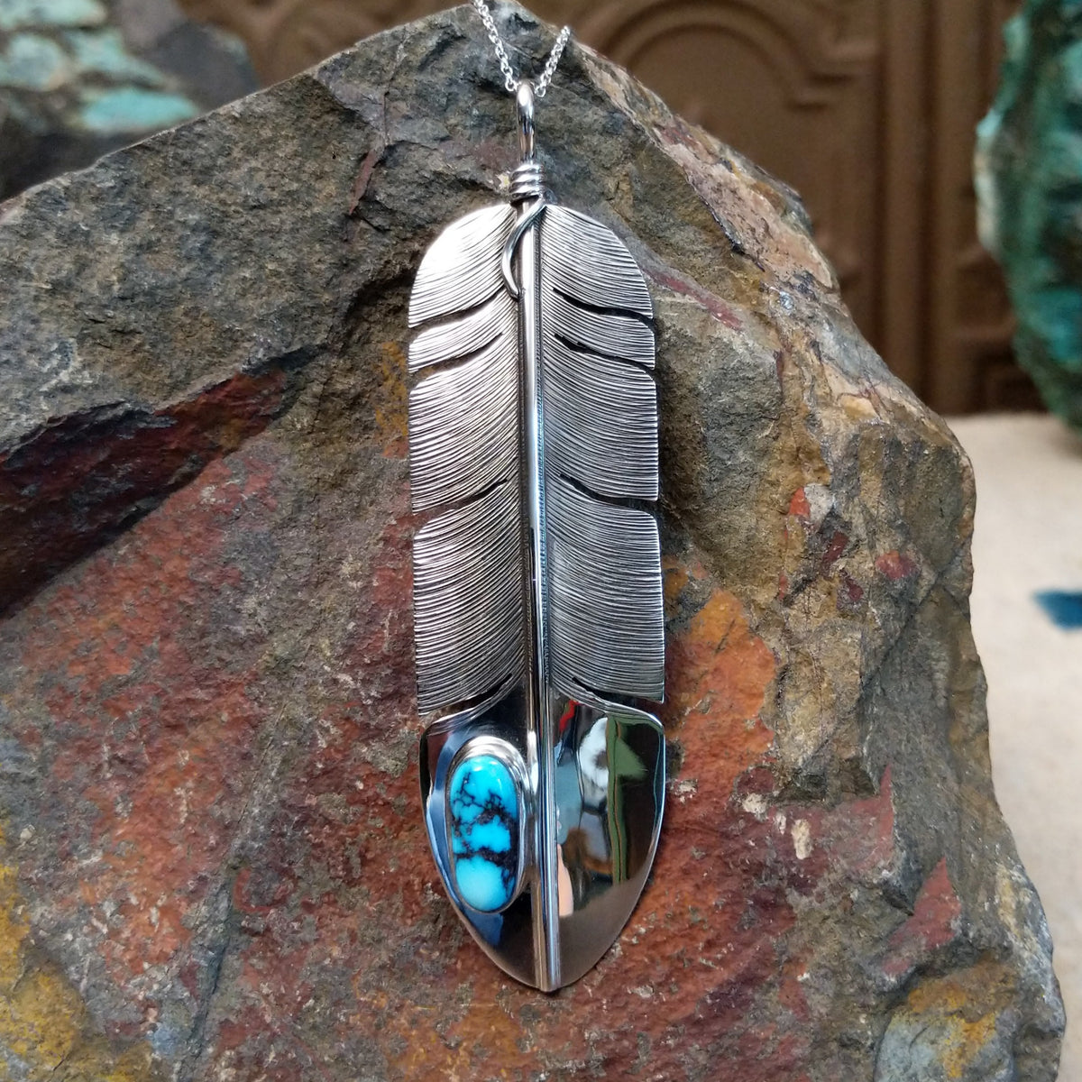 Kingman Turquoise feather pendant by Lena Platero featuring a detailed silver feather with etched texture, polished accents, and an oval turquoise stone with dark matrix.