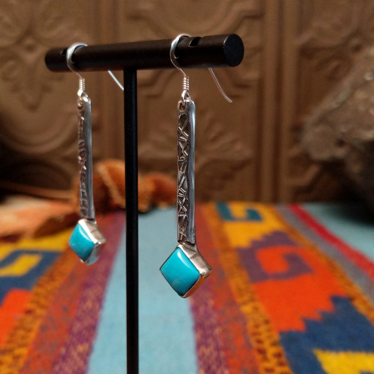 Everett & Mary Teller Kingman Turquoise earrings featuring vibrant turquoise stones, stamped Sterling Silver drops, and decorative silver beads; side view.
