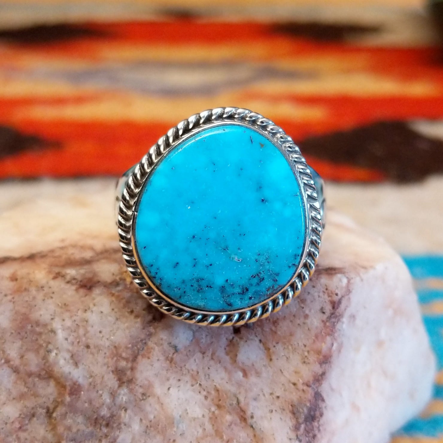 Sterling silver ring with Kingman turquoise set in the round bezel, framed by twisted rope detailing.