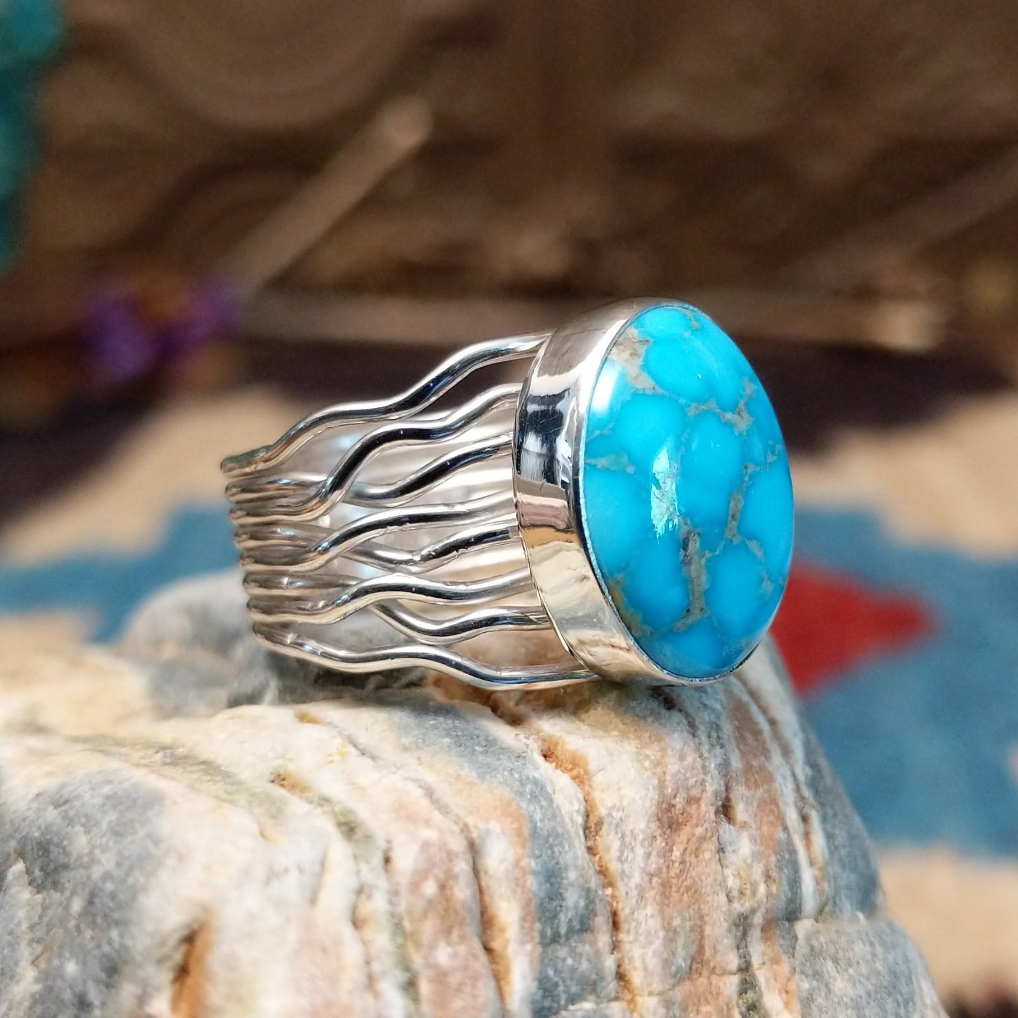 Sterling silver ring with Kingman turquoise set in a round bezel and strands of silver making up the band.