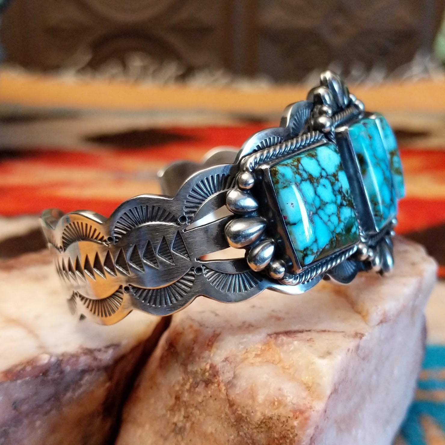 This sterling silver cuff bracelet features Kingman turquoise set in square bezels, framed by twisted rope and unique silverwork accents.