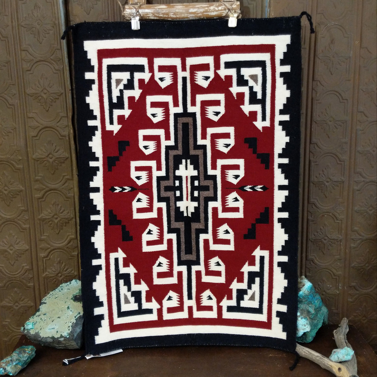 This handmade Navajo rug by Irene Eskee features a central motif with intricate geometric designs emanating outward.