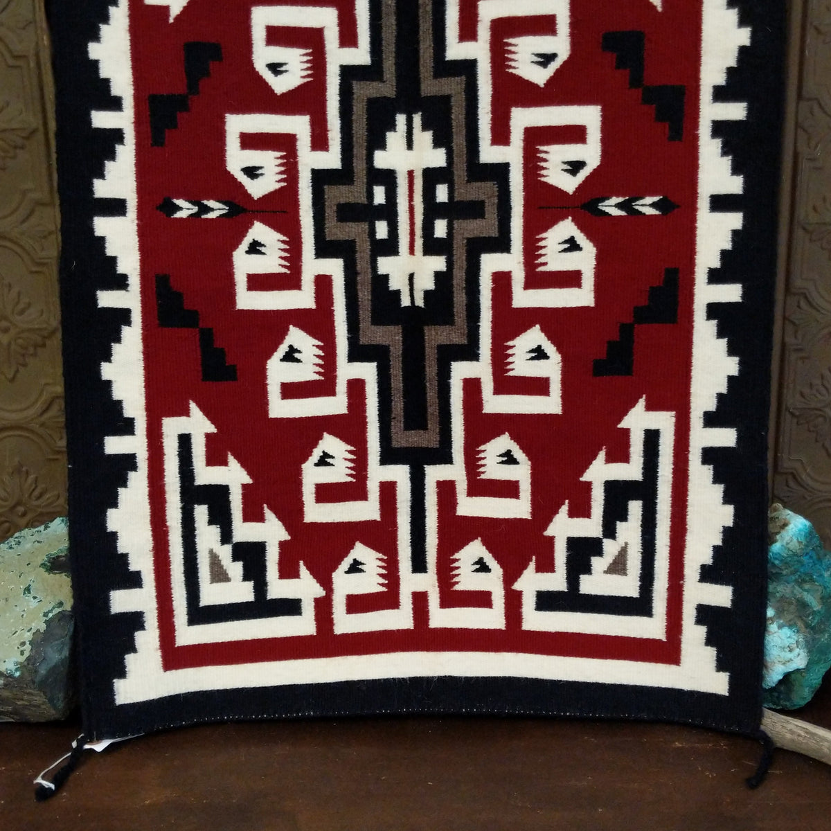 This handmade Navajo rug by Irene Eskee features a central motif with intricate geometric designs emanating outward.