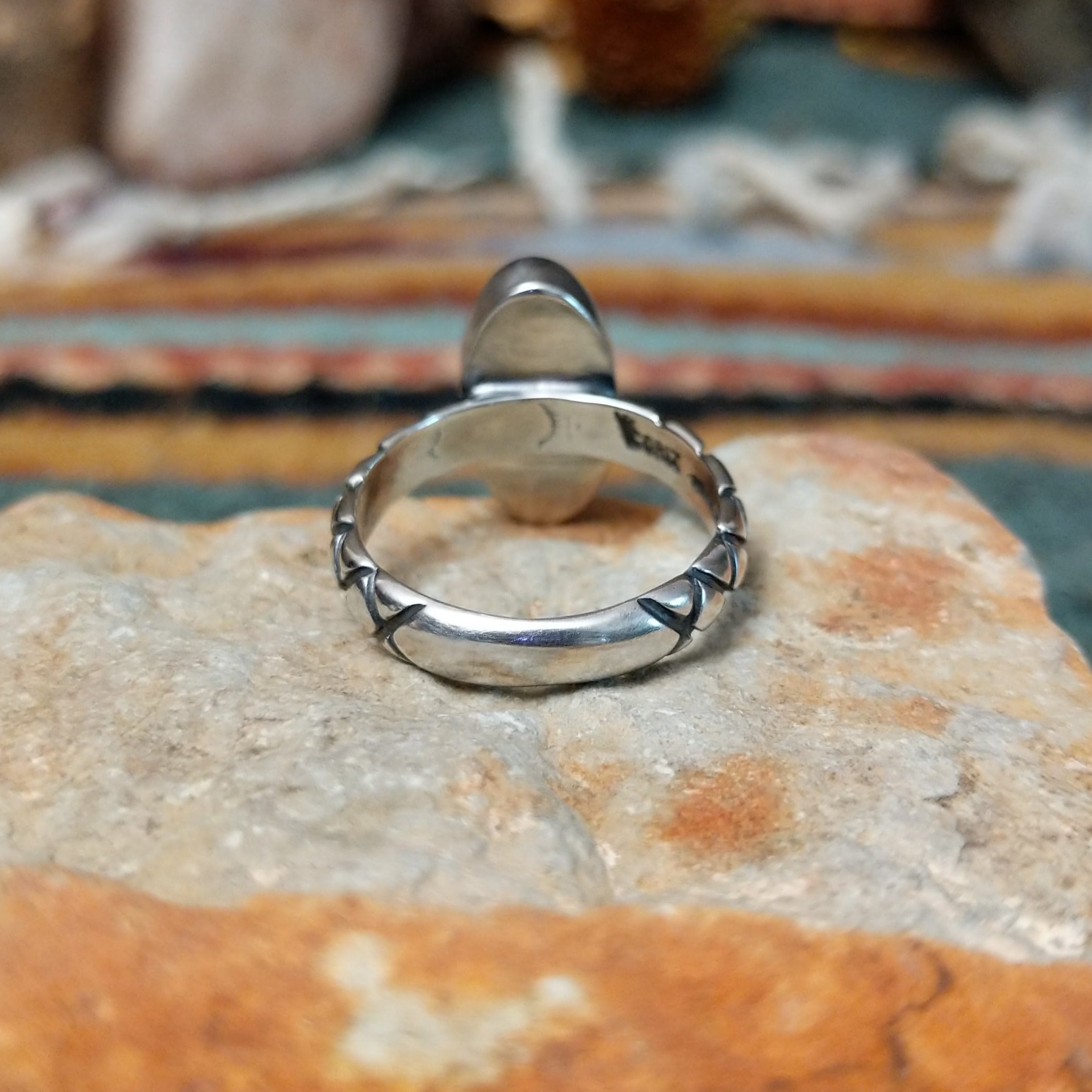 Raymond Coriz sterling silver ring featuring an elongated oval green malachite cabochon with natural dark banding and a textured knurled silver band; underside view.