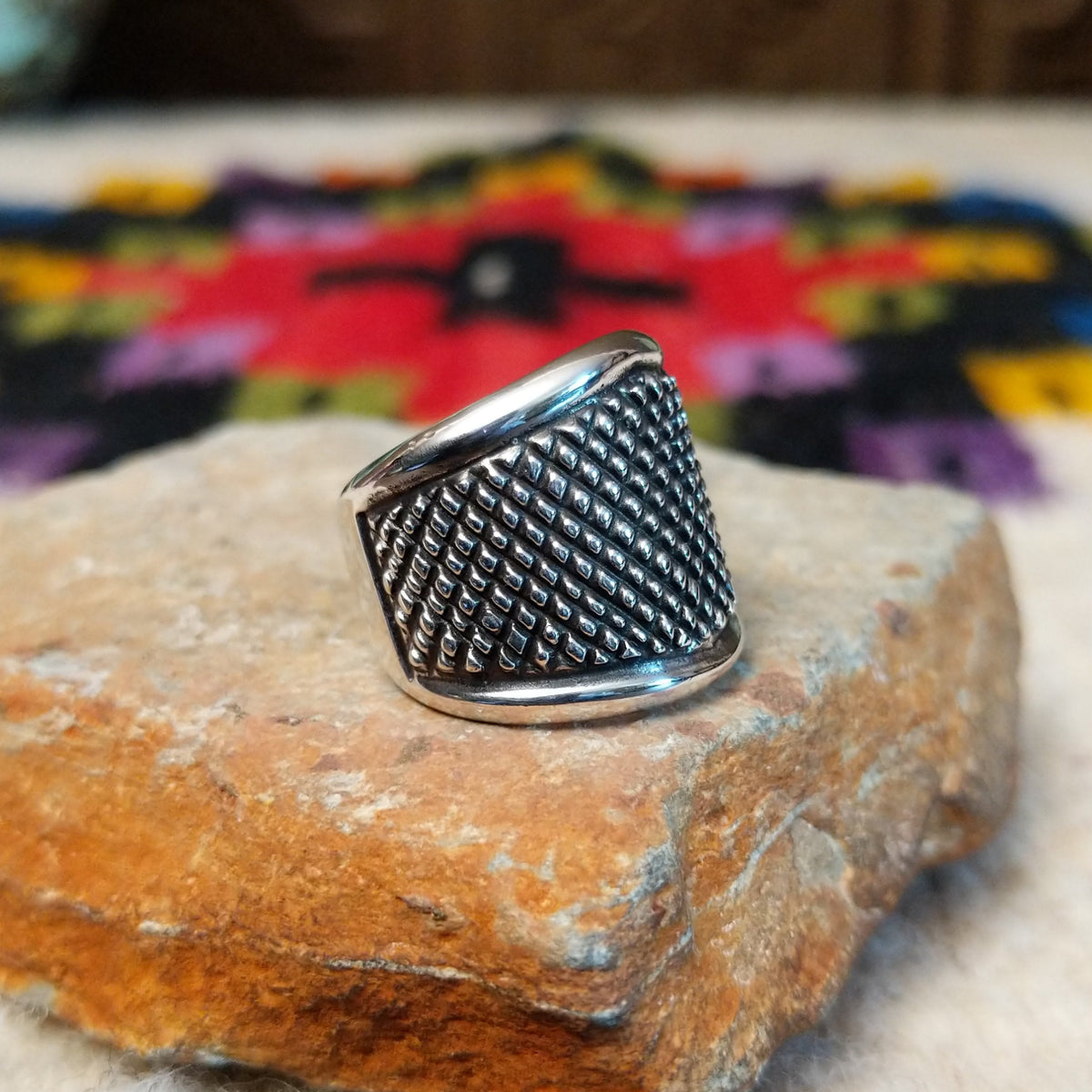 This distinctive Silver Ring by Raymond Coriz features a wide silver band with a raised crosshatch pattern, oxidized detailing, and smooth polished borders along the top and bottom; side view.