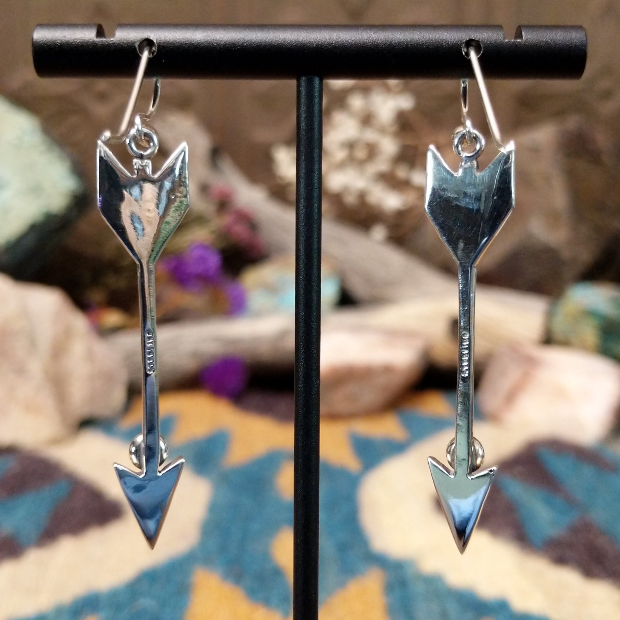 Handcrafted sterling silver arrow dangle earrings by Raymond Coriz featuring round lapis accents, textured arrowheads, and polished silver hooks; artisan and Sterling Silver stamp.