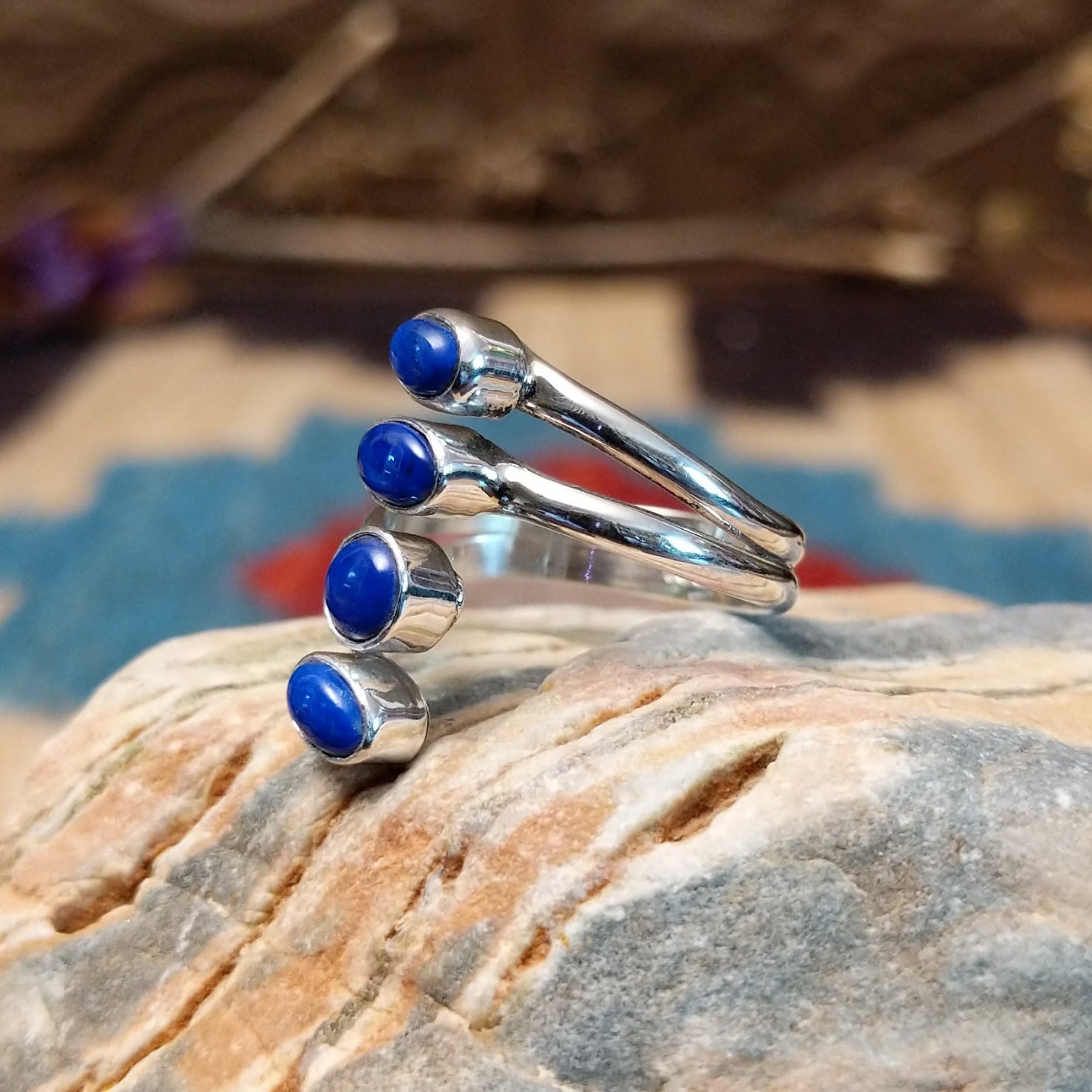 Sterling silver ring with lapis set in four bezels, each suspended on the strands of the band.