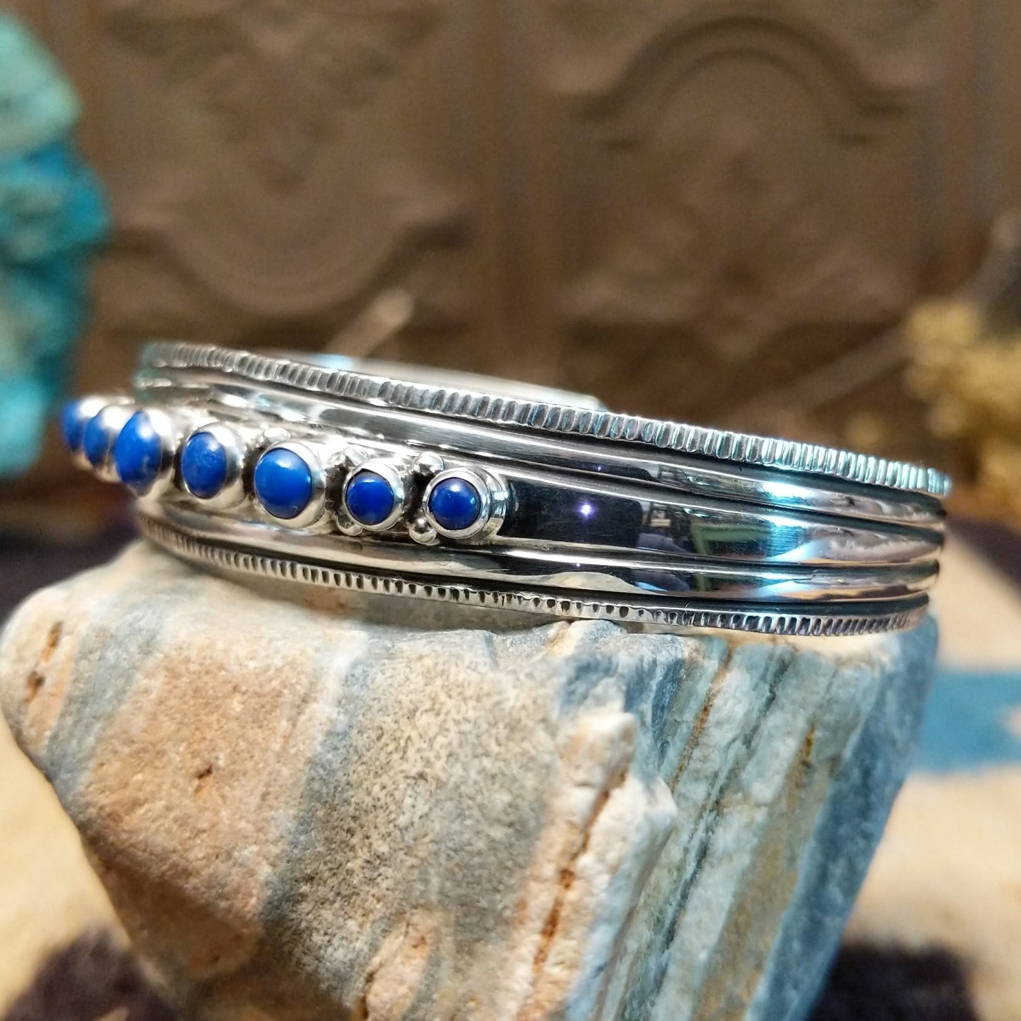 Sterling silver cuff bracelet with lapis set in bezels lined across the surface and stamping.