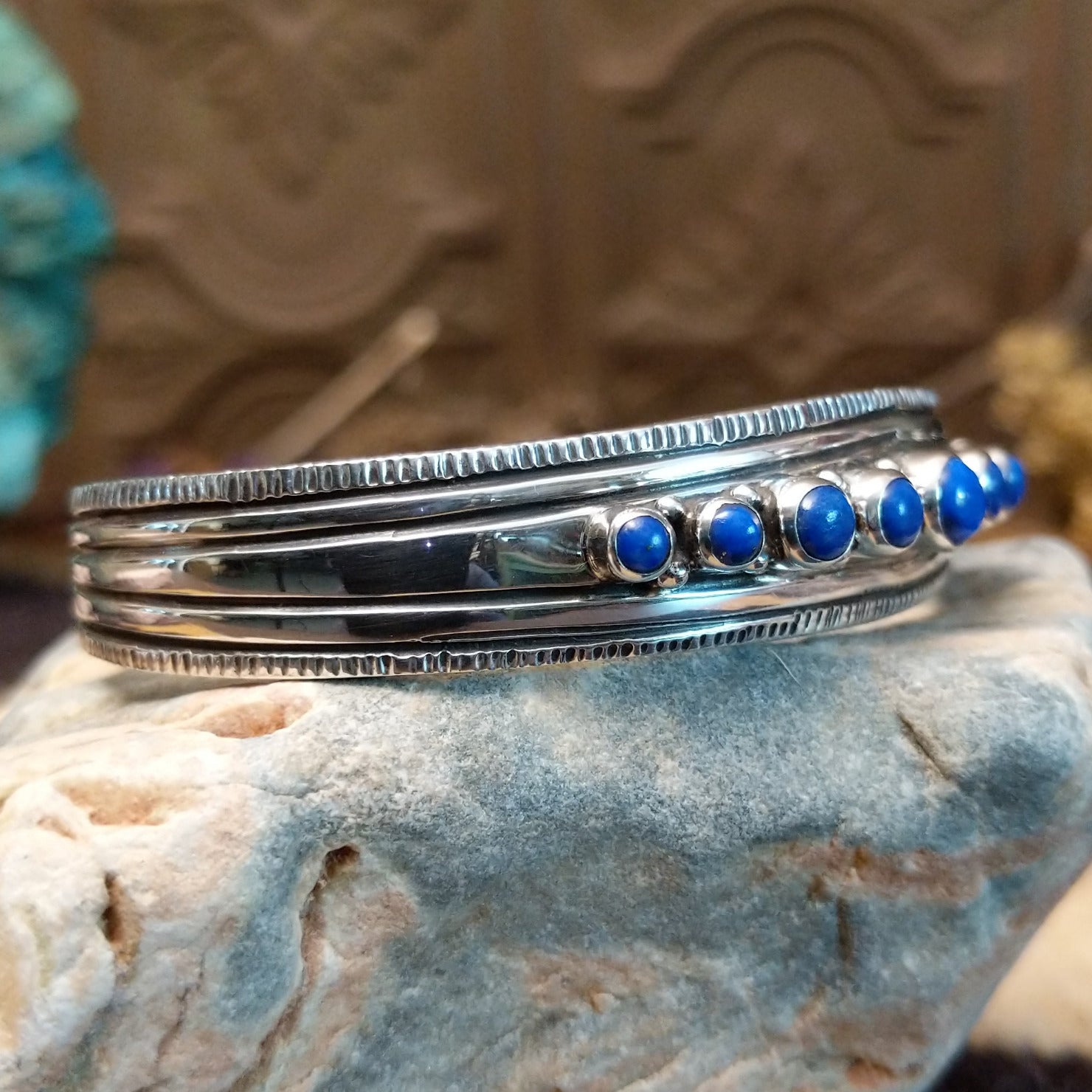Sterling silver cuff bracelet with lapis set in bezels lined across the surface and stamping.
