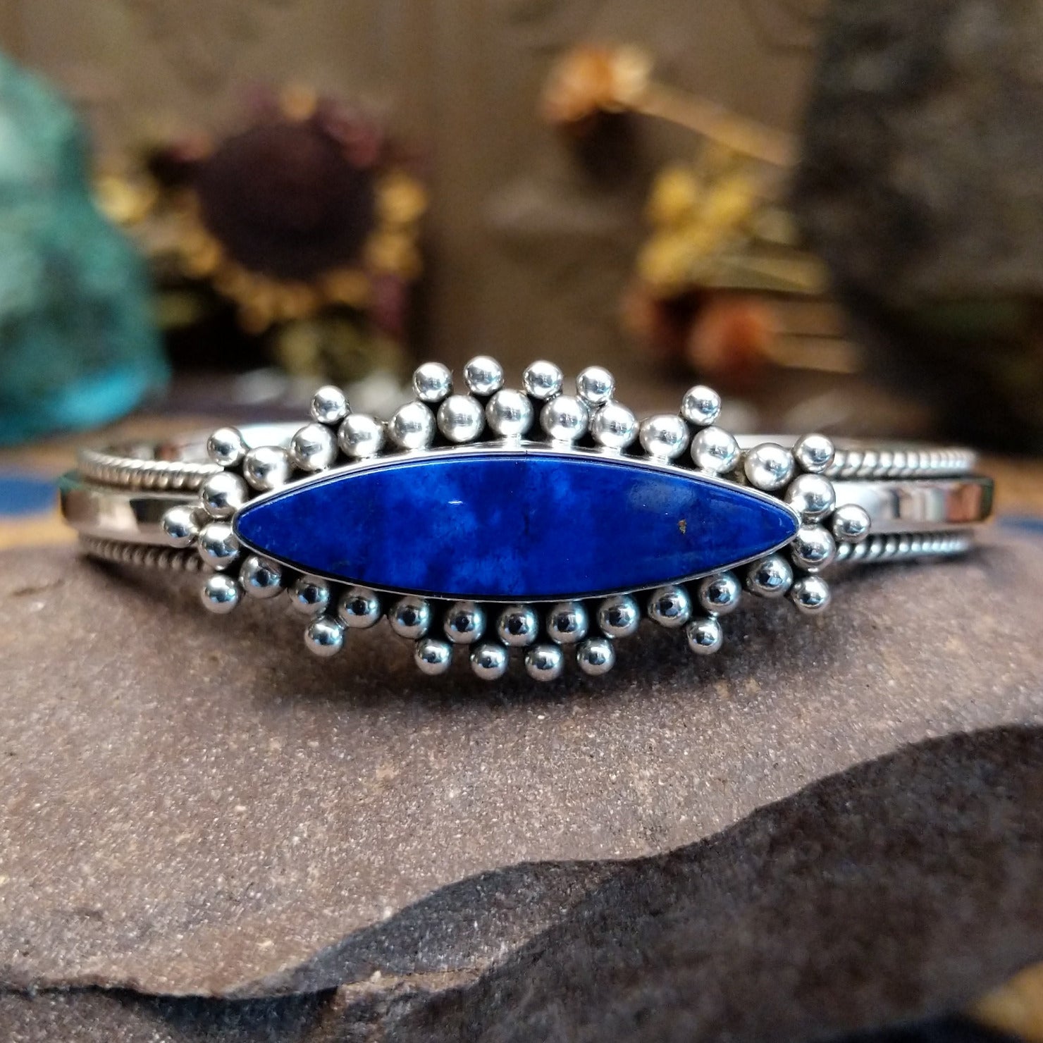 Sterling silver cuff featuring a navette-shaped lapis stone with silver beadwork and twisted rope detailing.