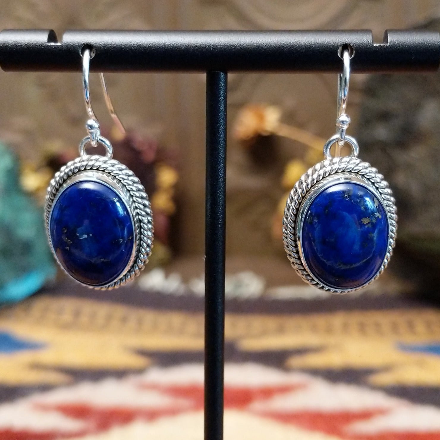 Sterling silver lapis lazuli dangle earrings featuring oval blue stones with twisted rope detailing and French hooks.