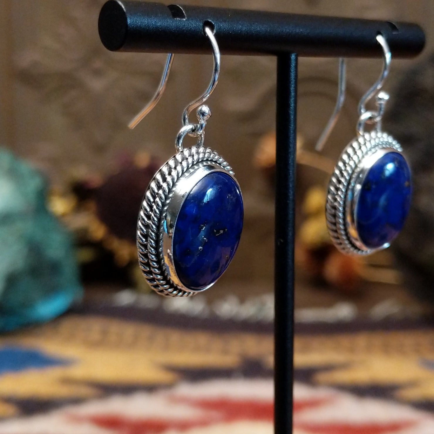 Sterling silver lapis lazuli dangle earrings featuring oval blue stones with twisted rope detailing and French hooks.