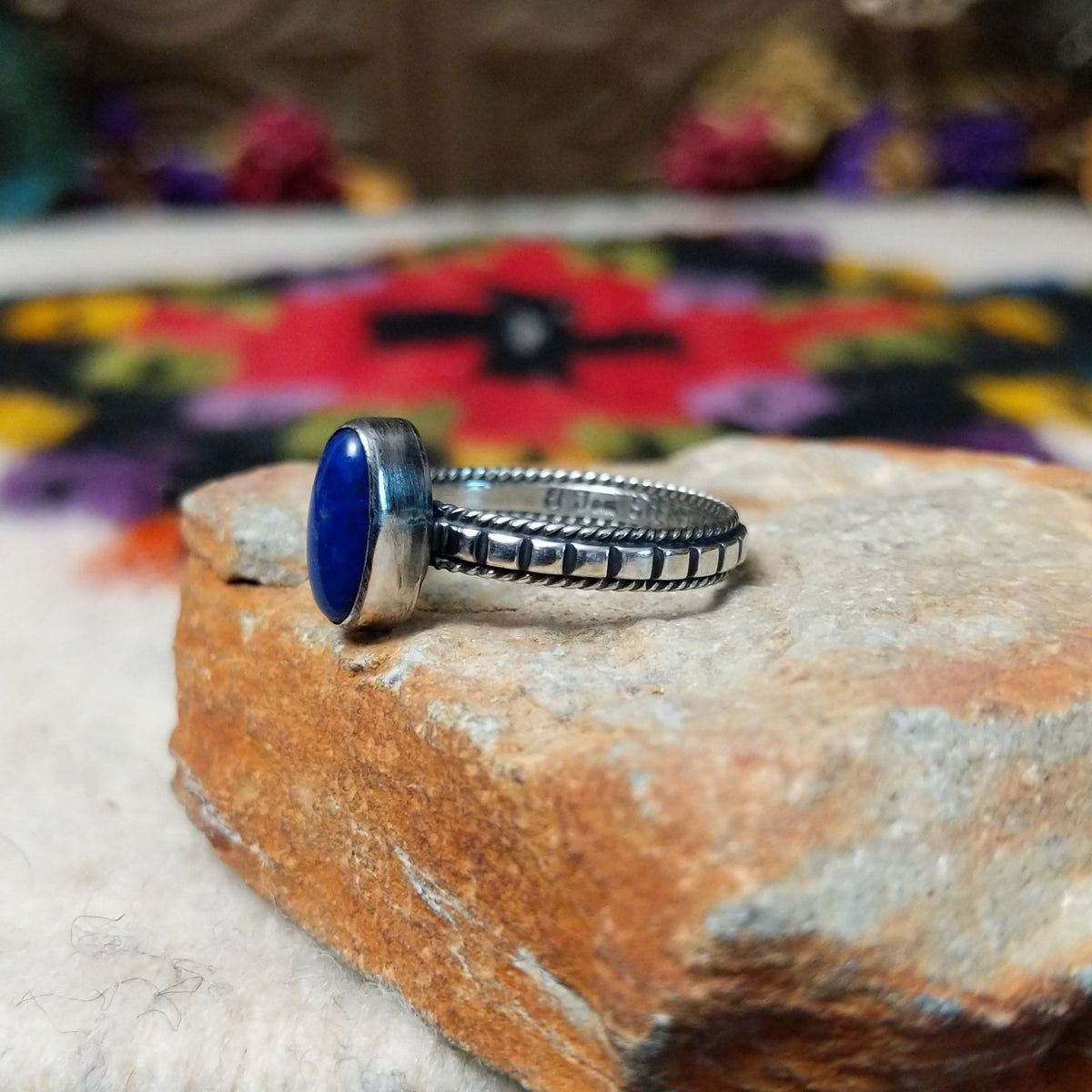 Elegant Lapis Oval Ring by Elgin Tom with an elongated deep blue lapis stone set in sterling silver with twisted-rope edging and oxidized band details; side view.