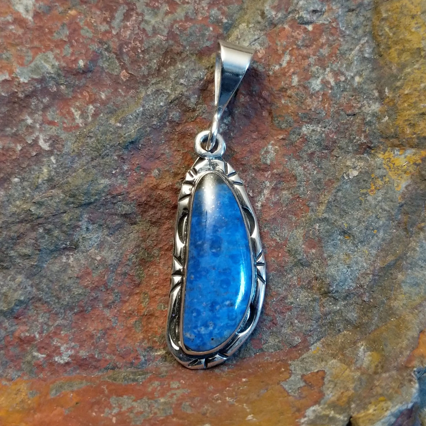 Sterling silver pendant with lapis set in the bezels and incised framing.